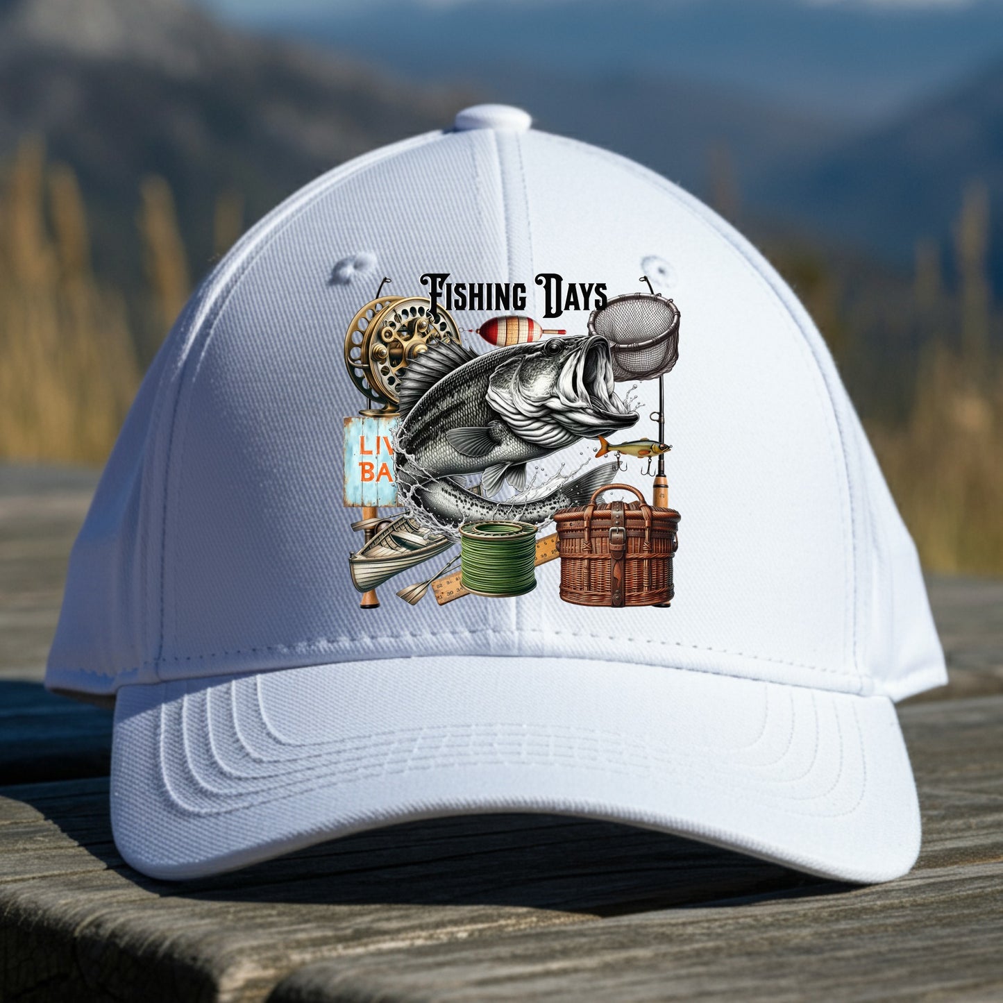 White cap with fishing-themed design on a wooden table with a mountain background
