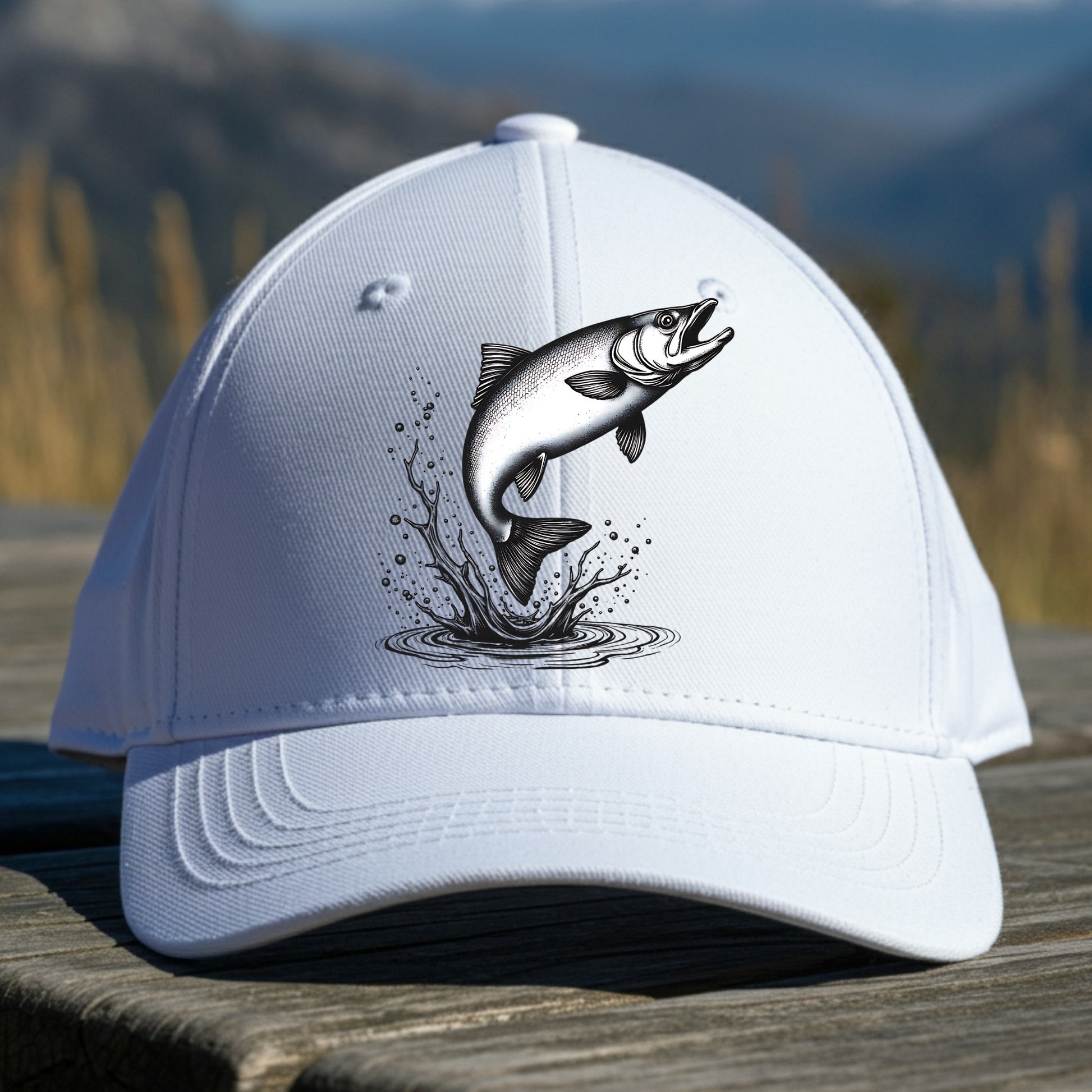 White cap with a salmon design on a wooden surface with a mountainous background
