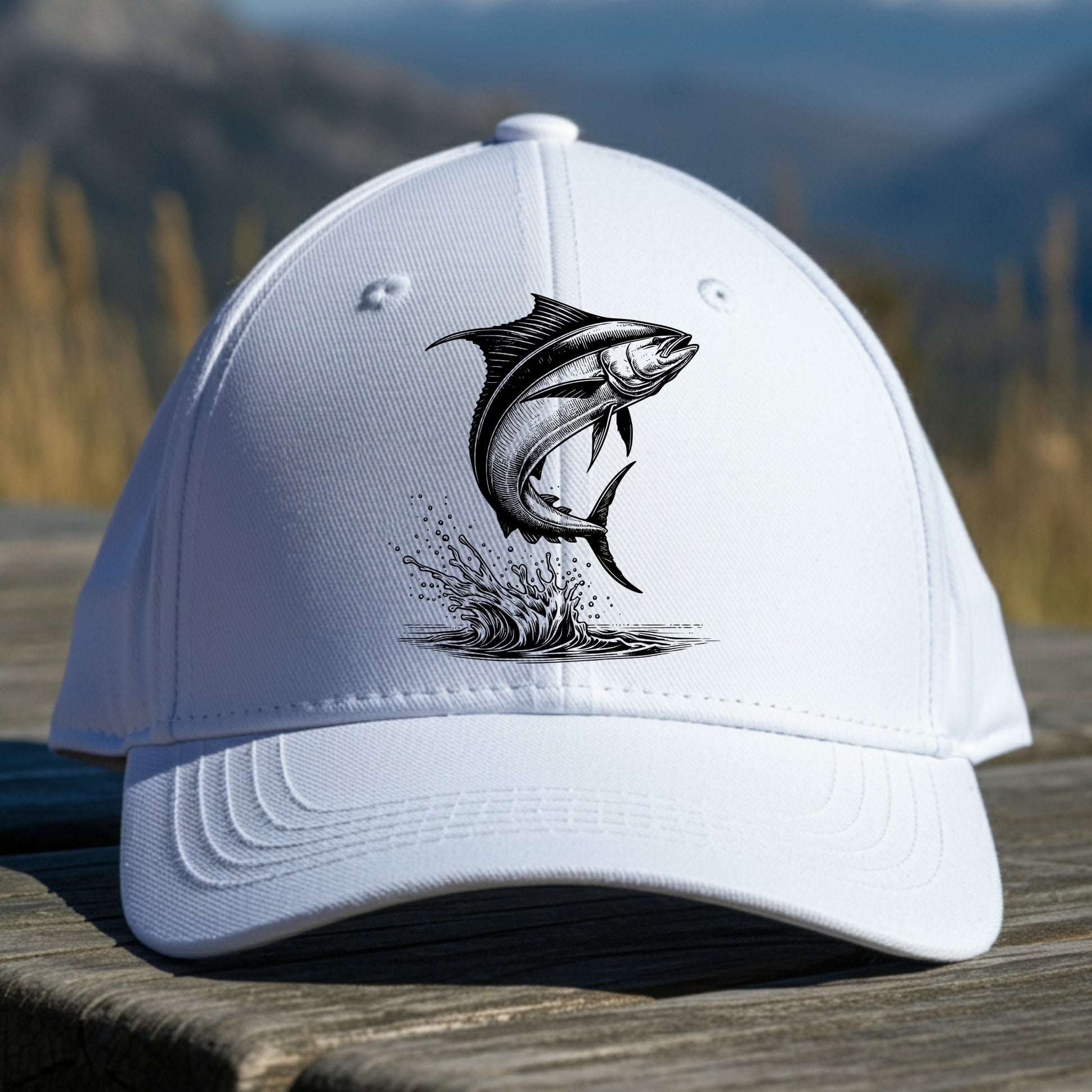 White cap with a mahi-mahi fish graphic on a wooden surface with a mountainous background