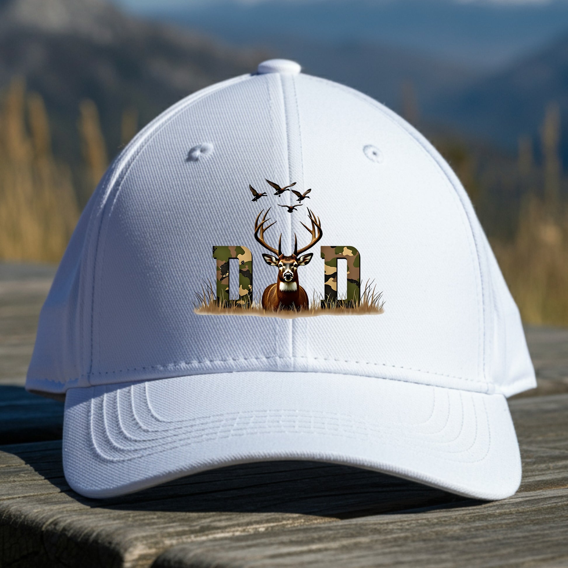 White cap with a deer and letter 'D' design on a wooden surface with a mountain background