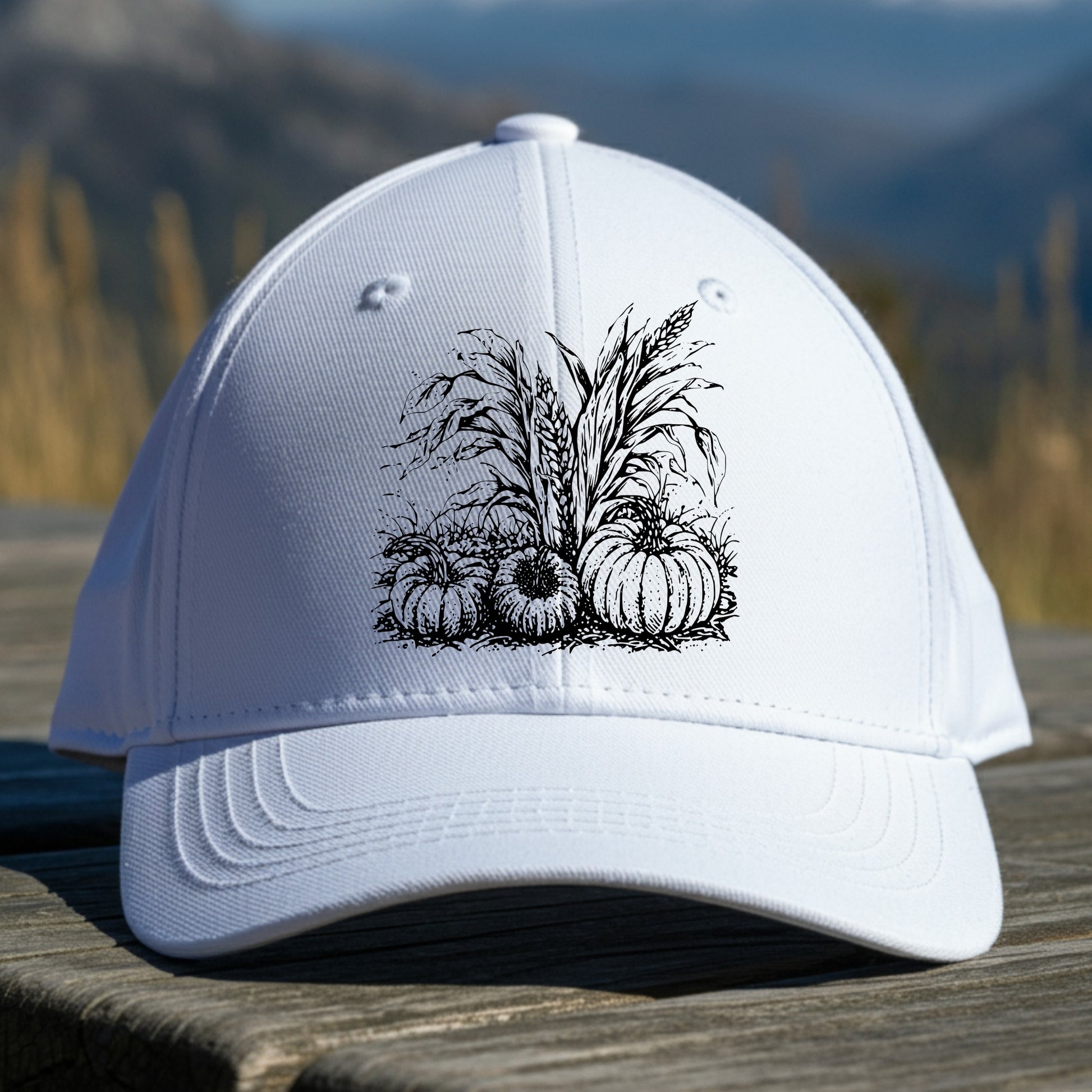 White cap with black pumpkin design on a wooden surface with a mountain background