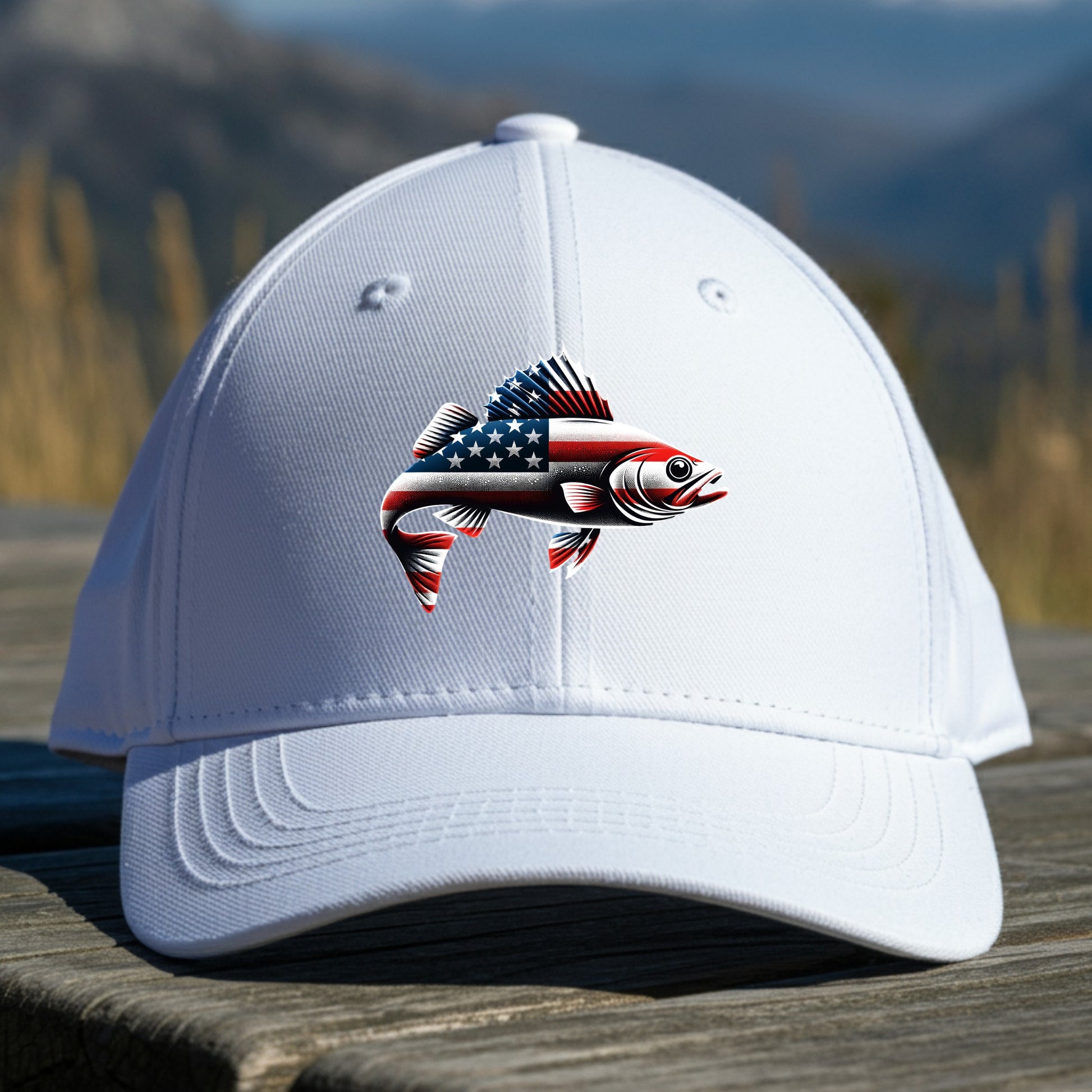 White cap with a walleye fish design featuring the American flag on a wooden surface with a mountain background.