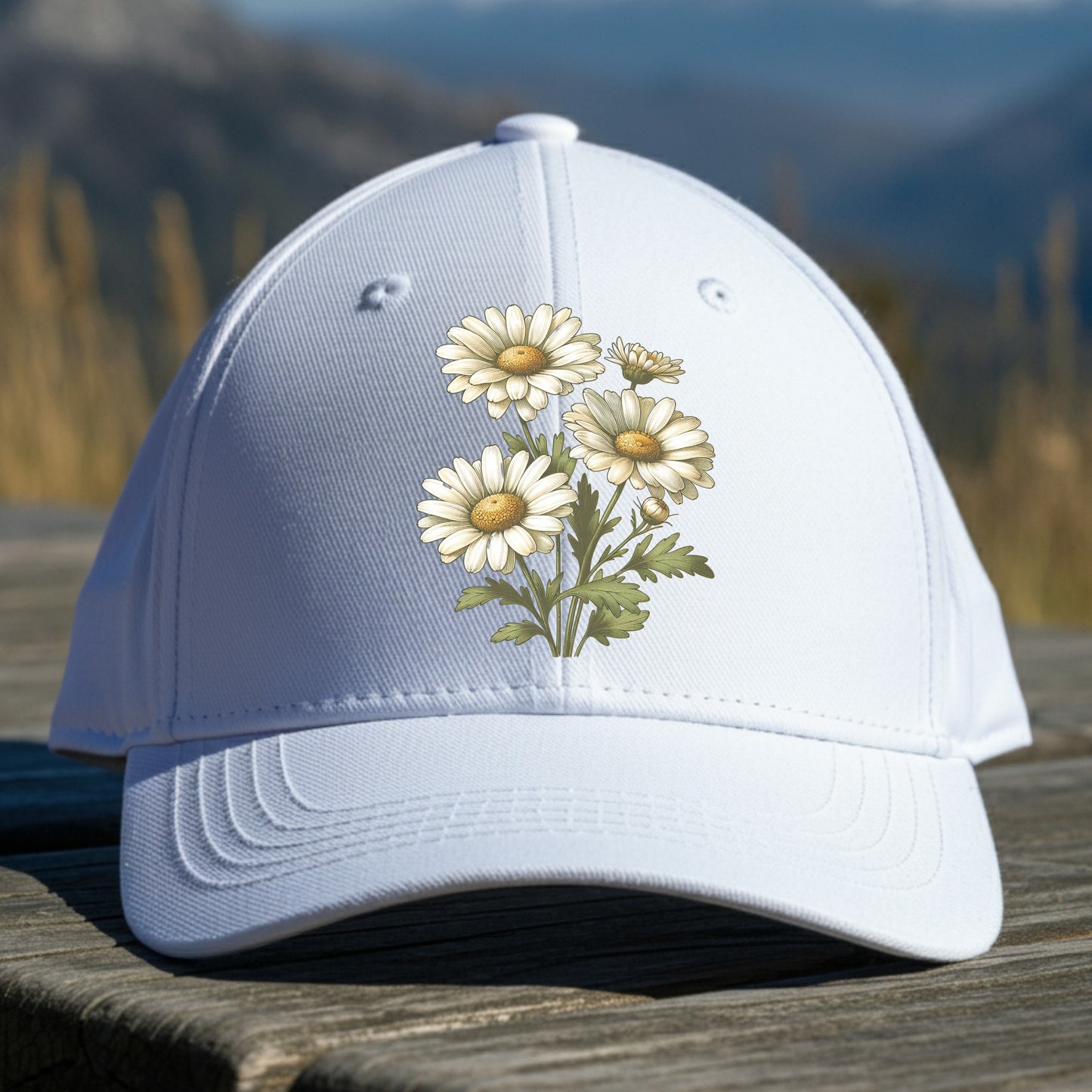 White cap with daisy floral design on a wooden surface with a mountainous background
