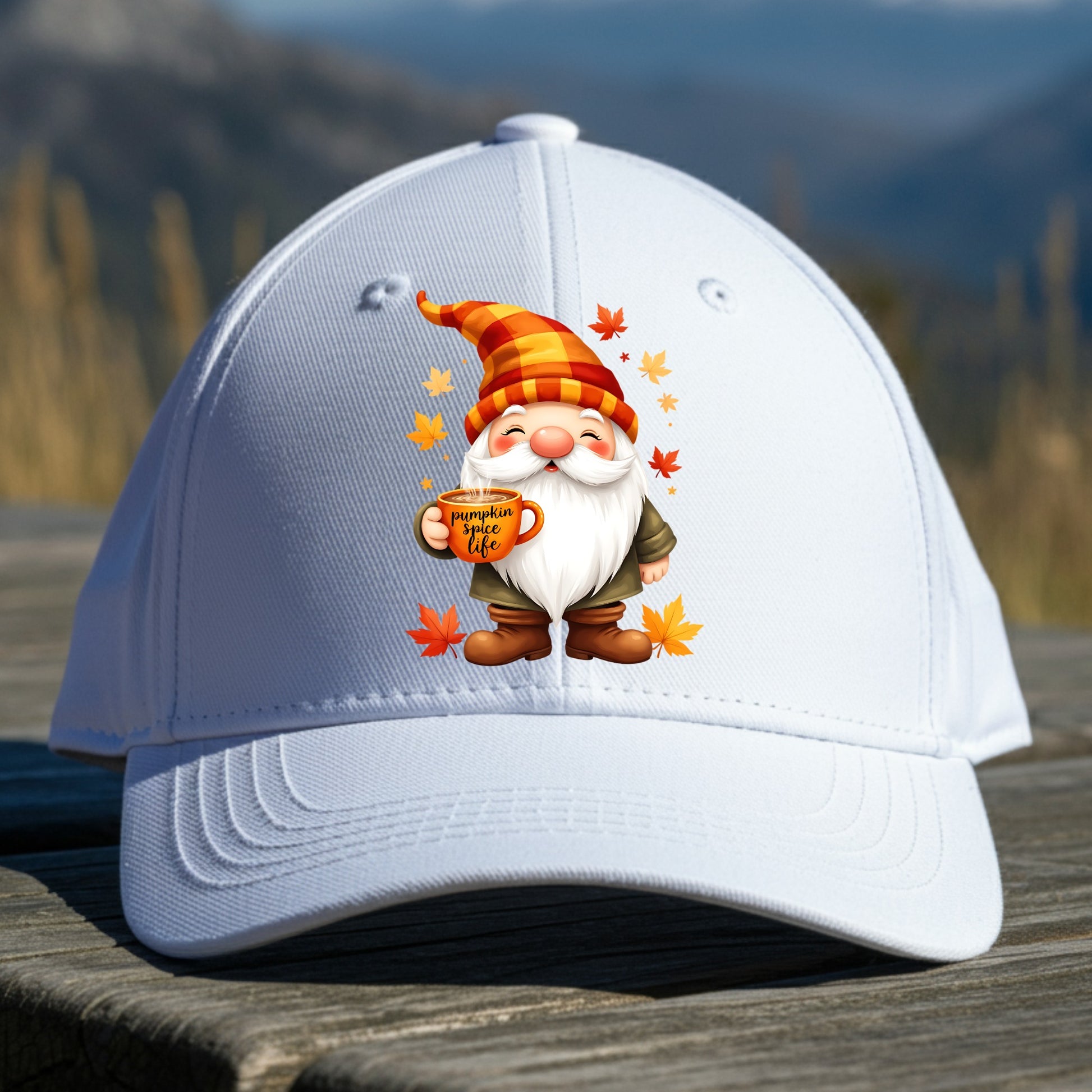 White cap with a cartoon gnome holding a coffee cup design, placed on a wooden surface with a mountainous background.