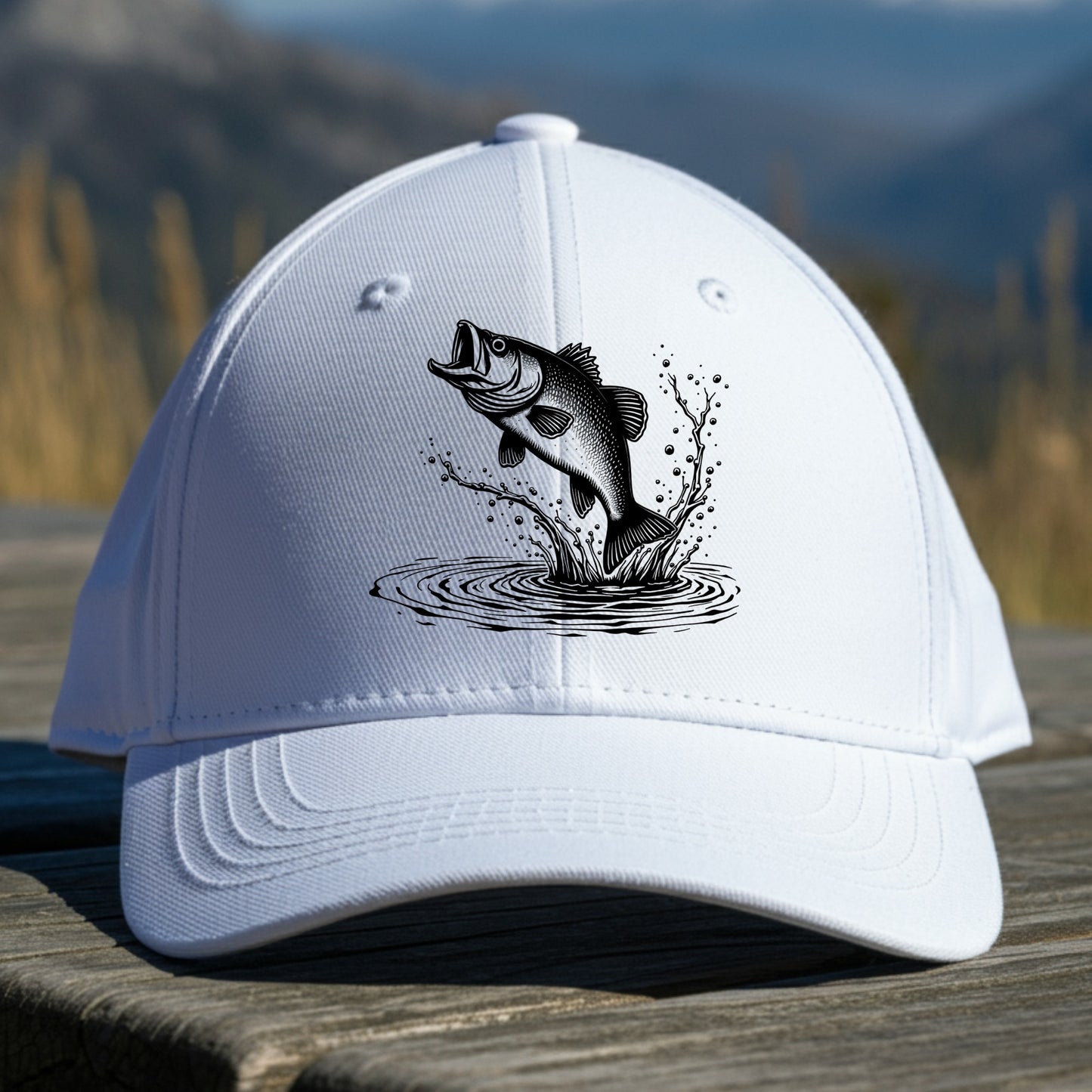 White cap with a largemouth bass fish graphic on a wooden surface with a mountainous background