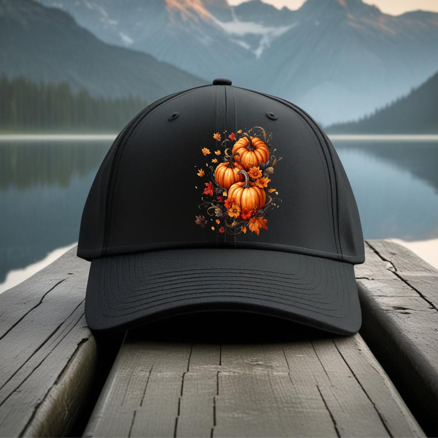 Black cap with pumpkin design on a wooden dock with a mountain and lake background