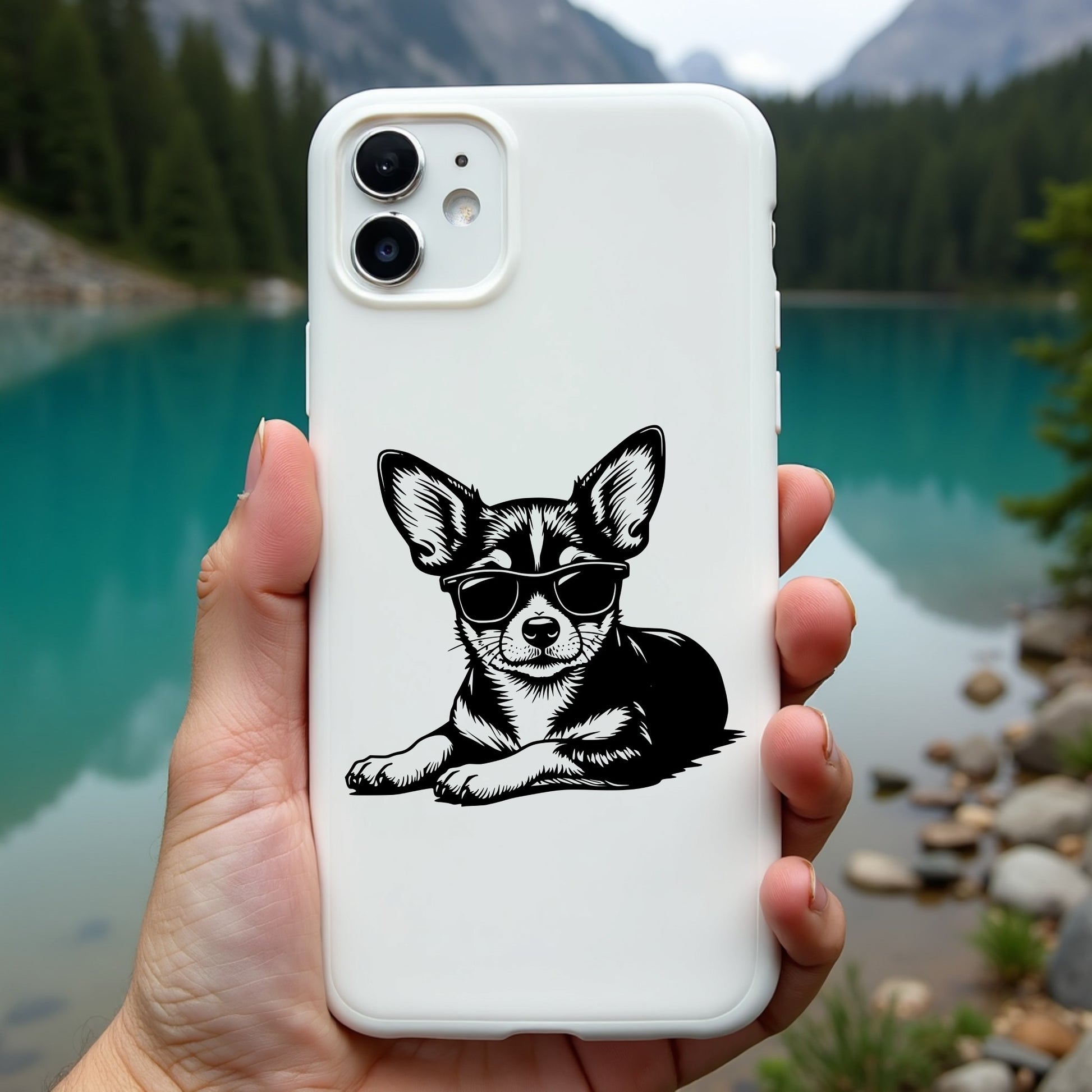 Phone case with a chihuahua design held in front of a scenic lake and mountains.