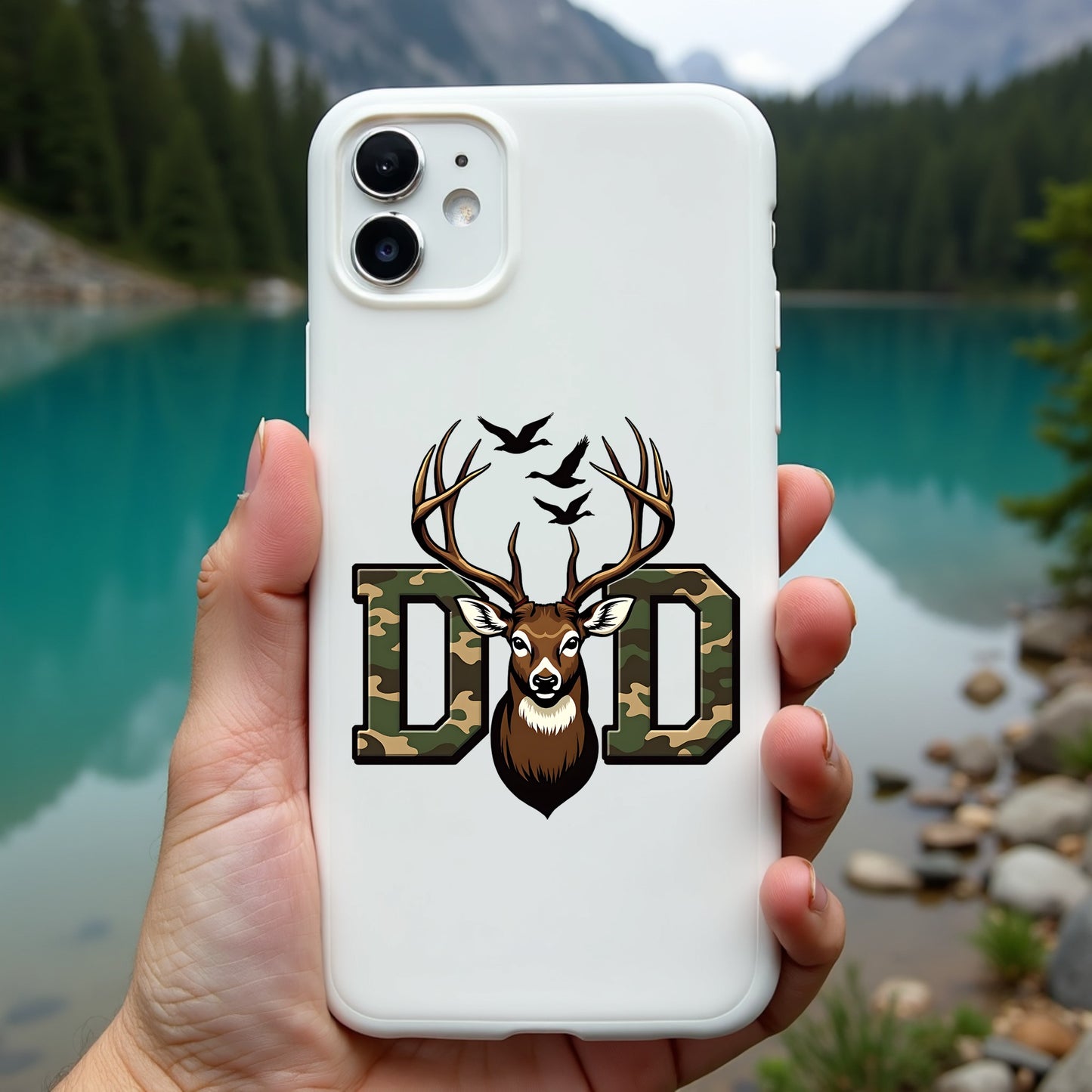 Phone case with deer design held in front of a scenic lake and mountains