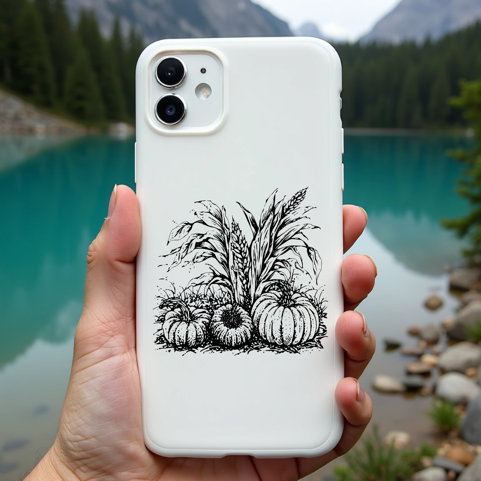 Phone case with pumpkin design held in front of a scenic lake and mountains