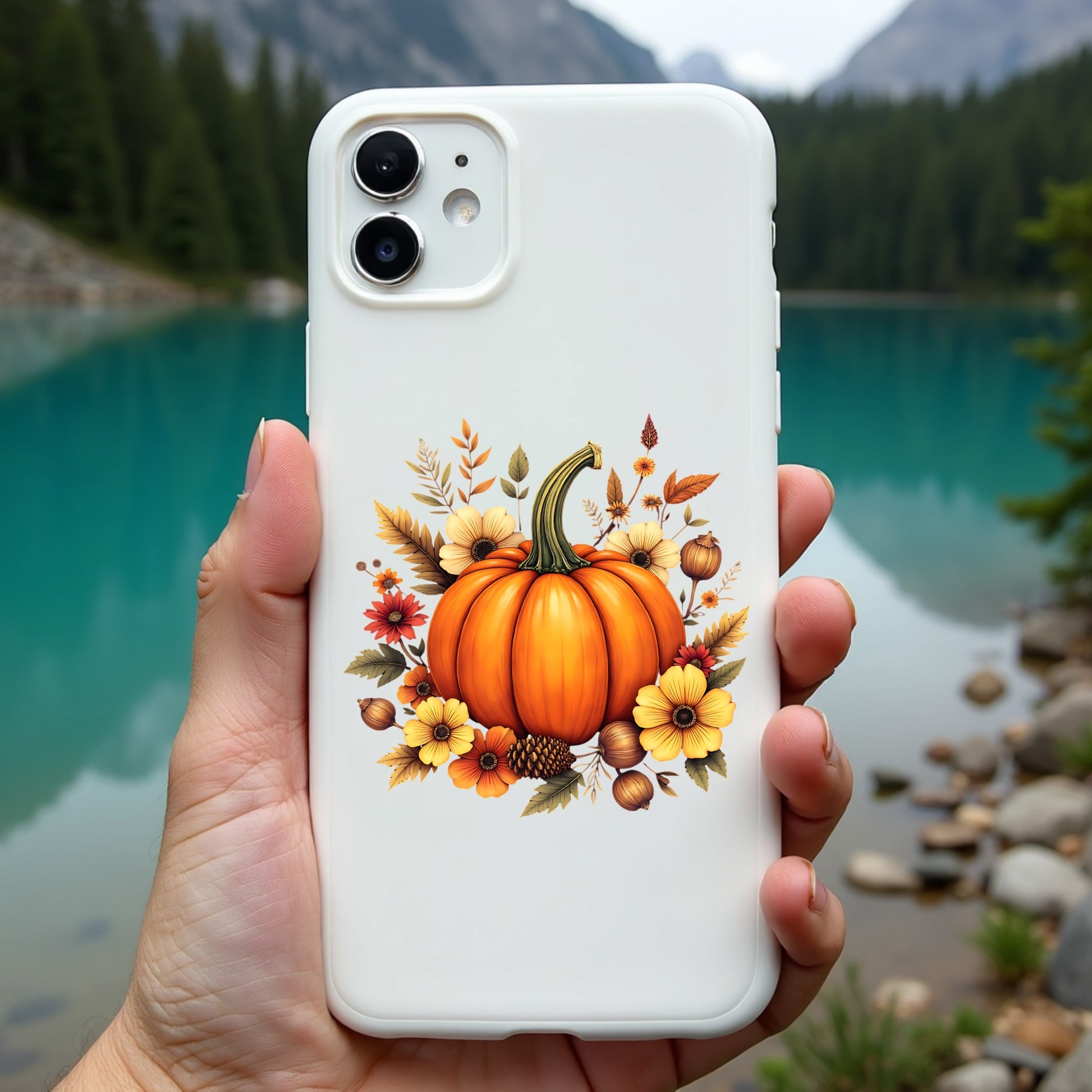 Phone case with pumpkin design held in front of a scenic lake and mountains