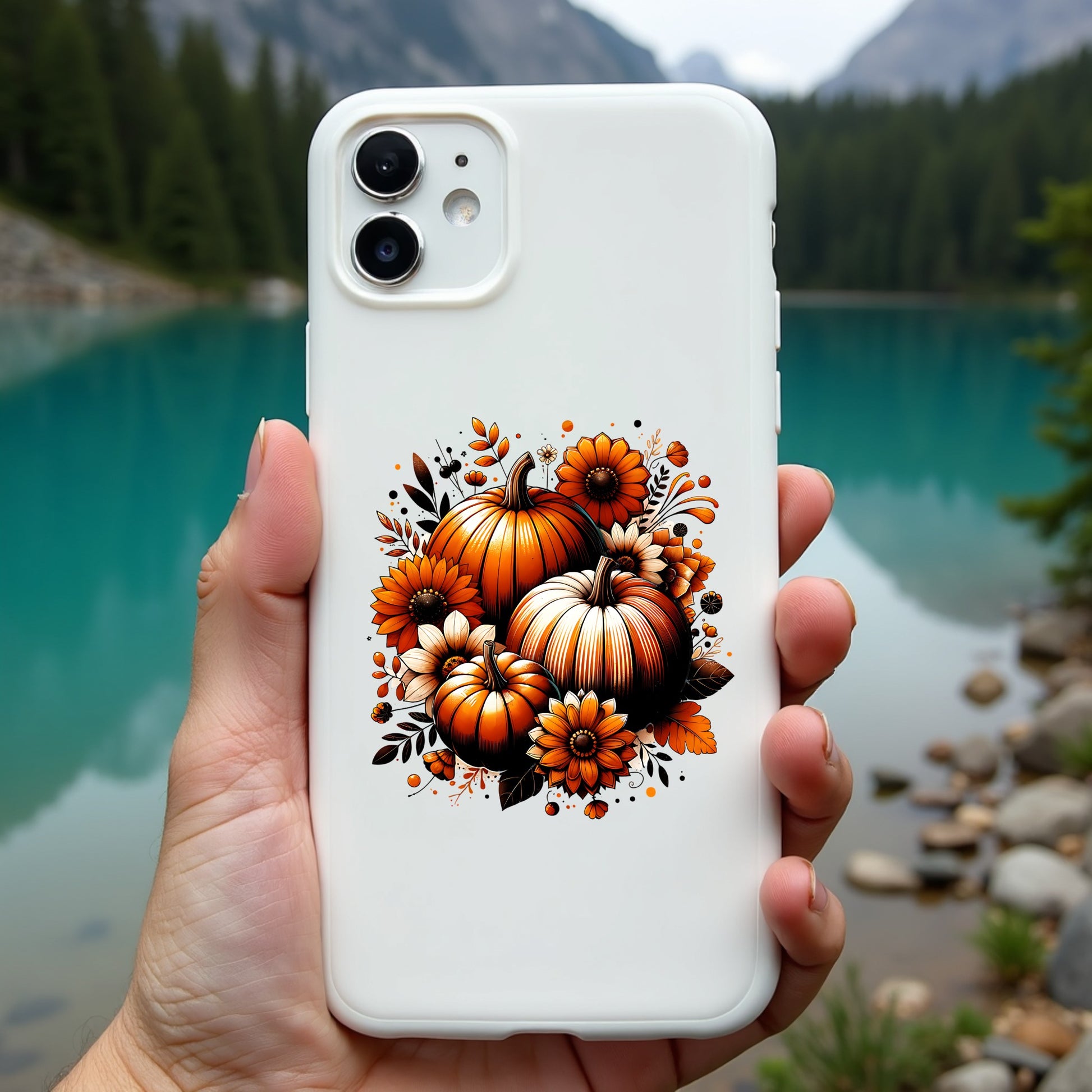 Phone case with pumpkin design held by a hand, mountain and lake background