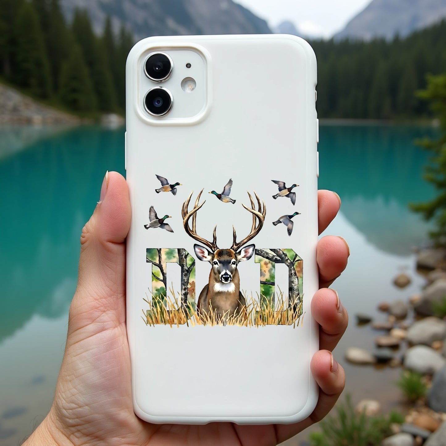 Phone case with deer design held in front of a scenic lake and mountains
