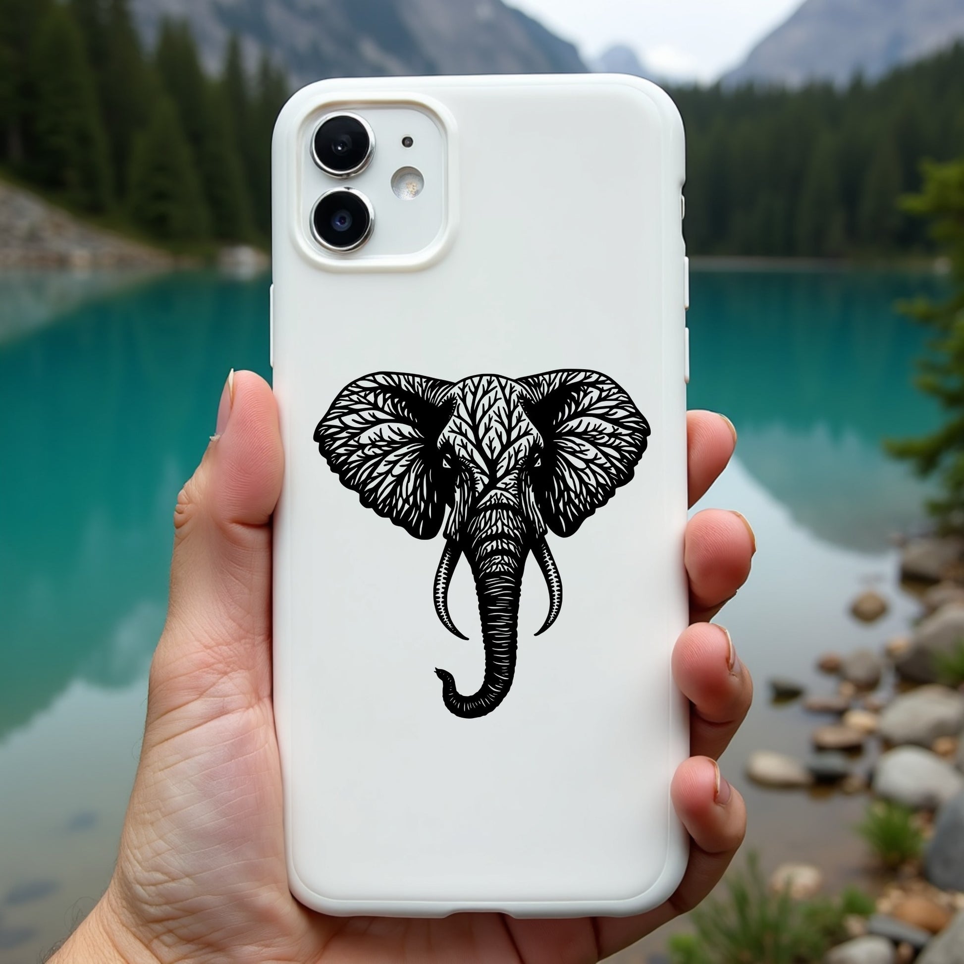 Phone case with elephant design held in front of a scenic lake and mountains
