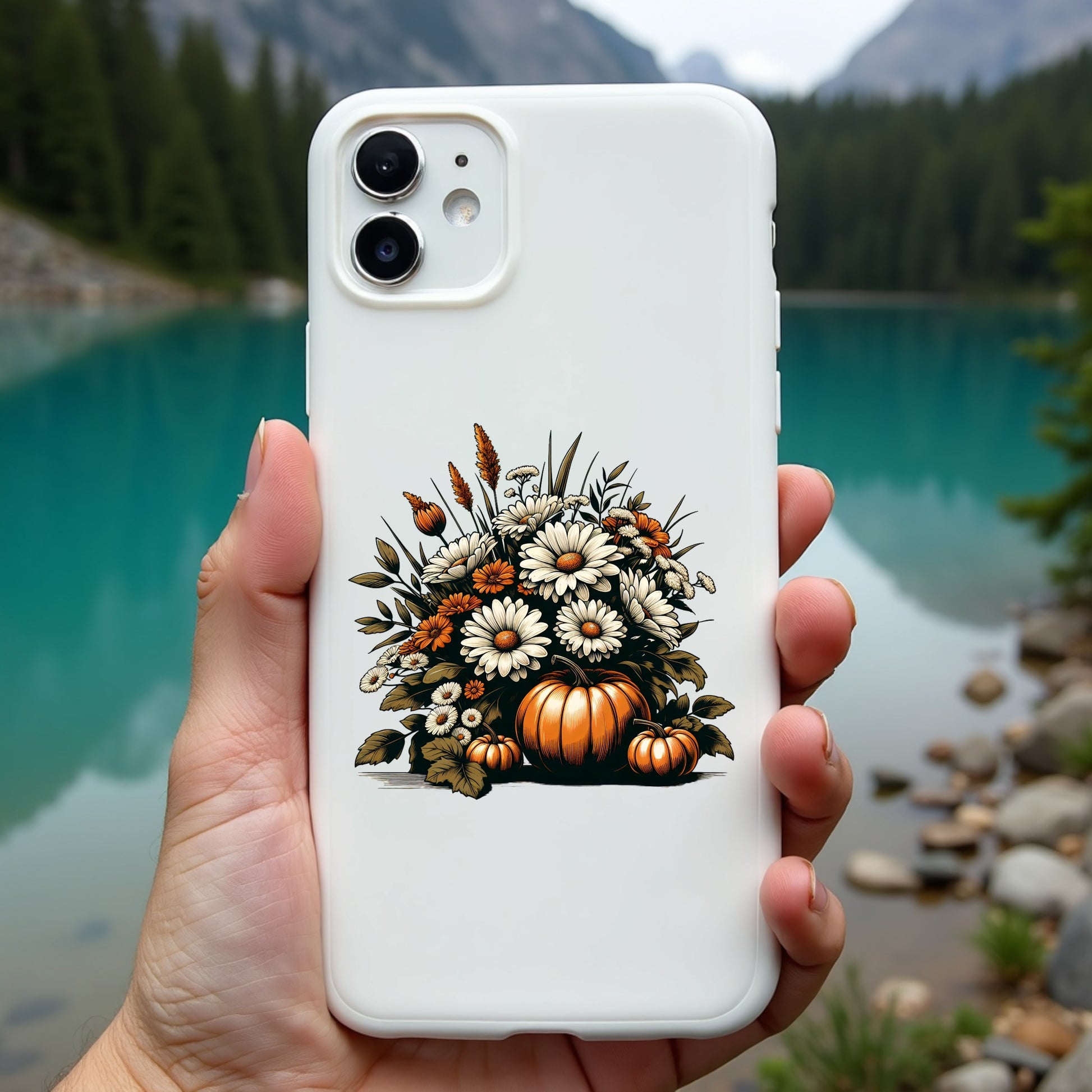 Phone case with autumn design held in front of a scenic lake and mountains