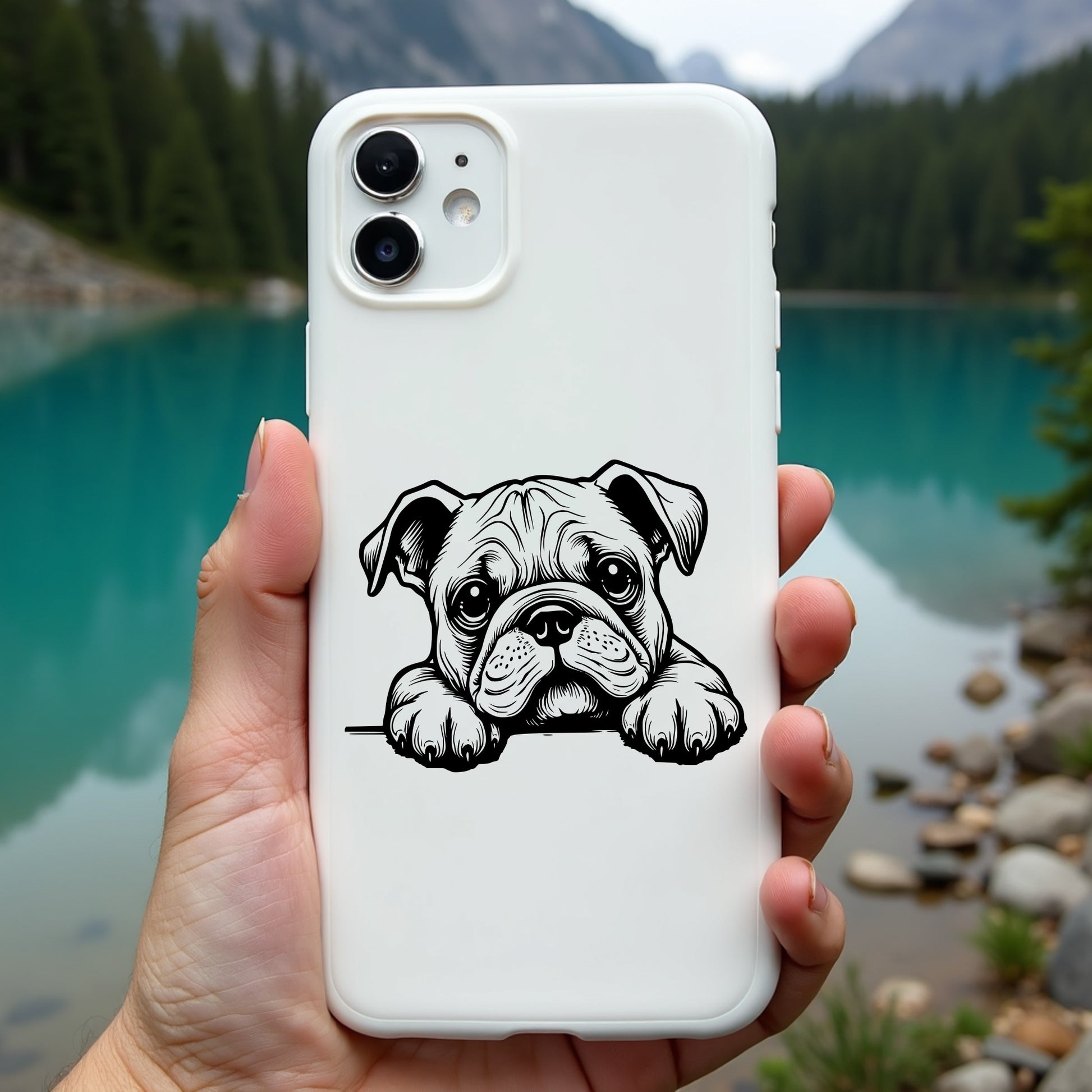 Phone case with a bulldog illustration held in front of a scenic lake and mountains.