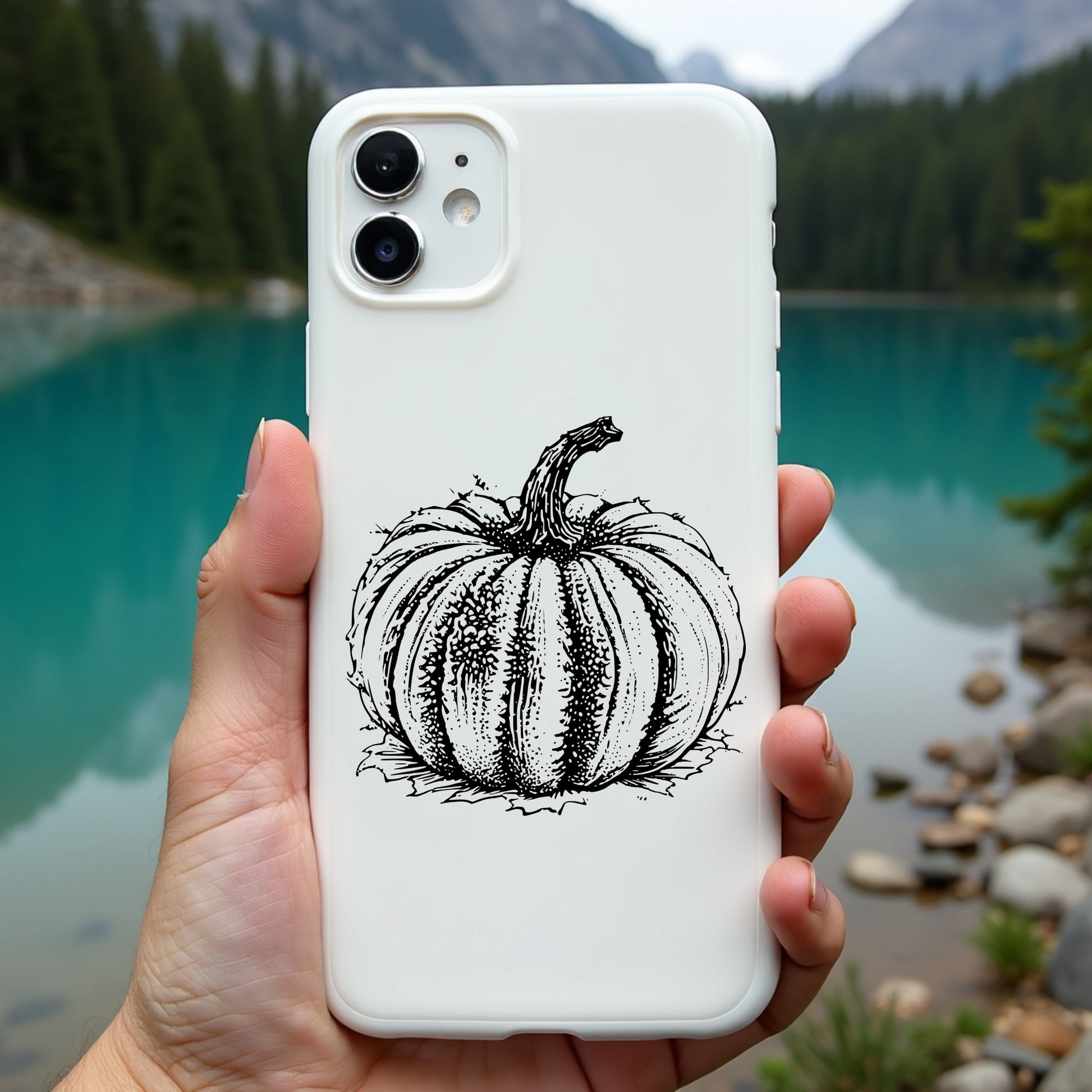 Phone case with pumpkin design held in front of a scenic lake and mountains