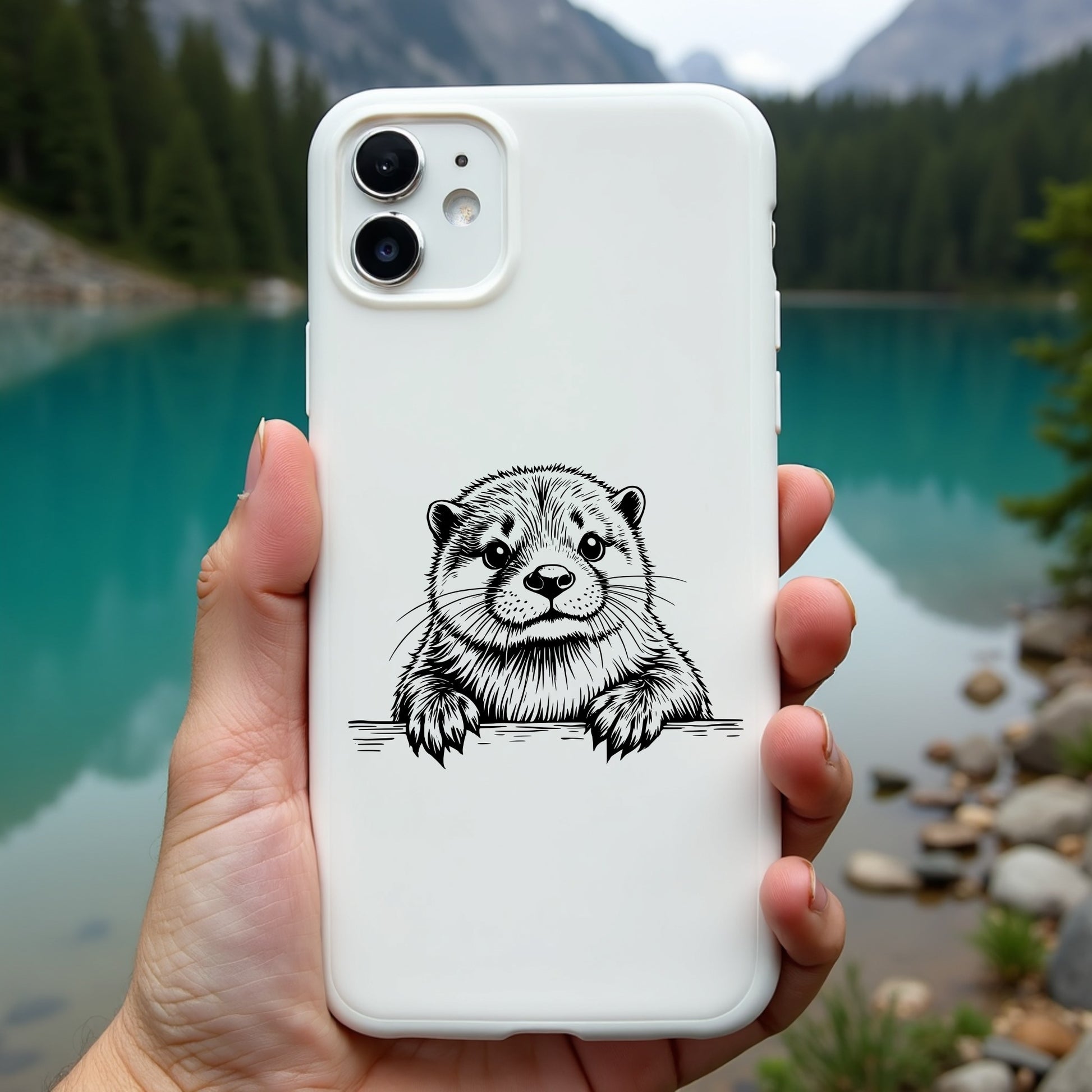 Phone case with otter design held in front of a scenic lake and mountains
