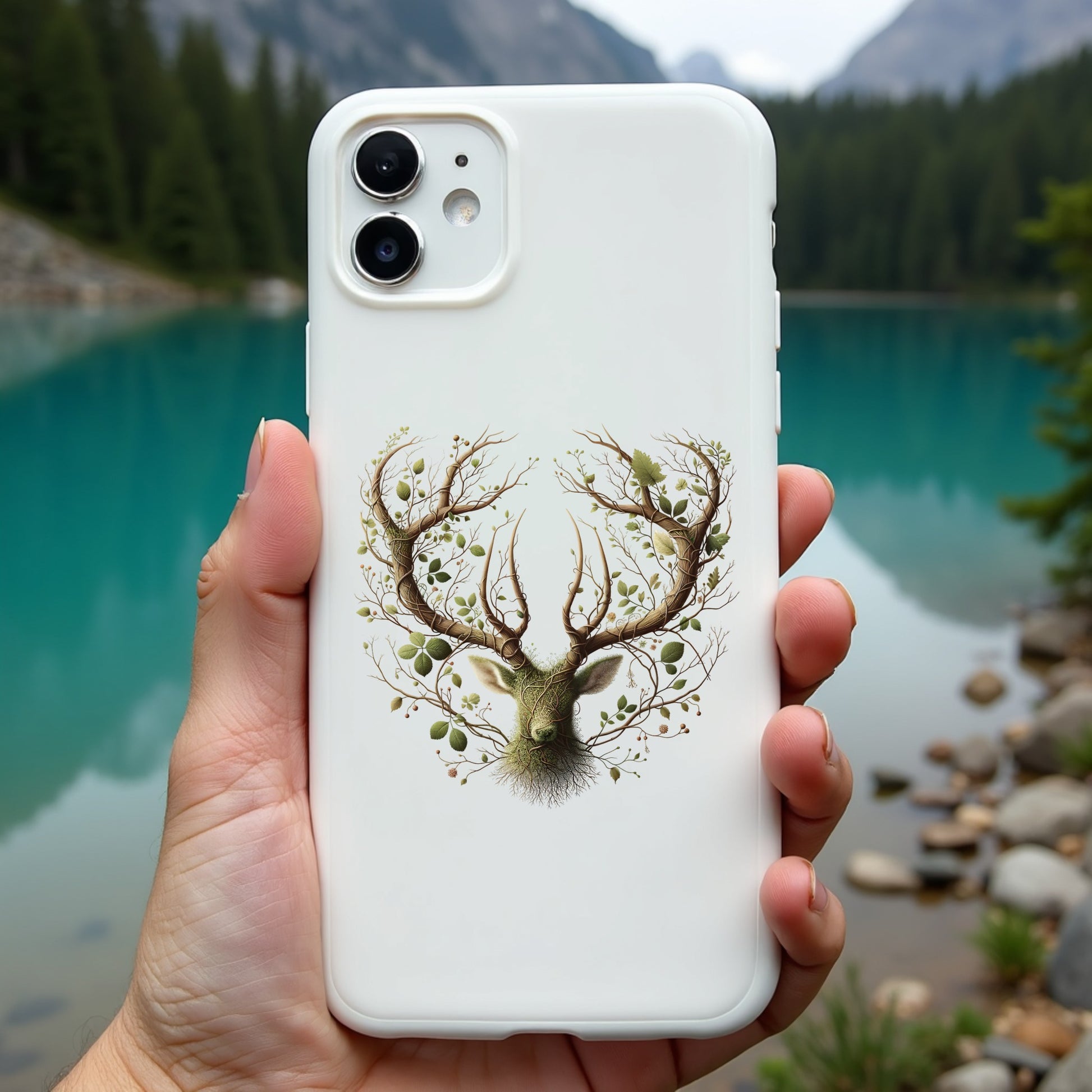 Phone case with deer design held in front of a scenic lake and mountains