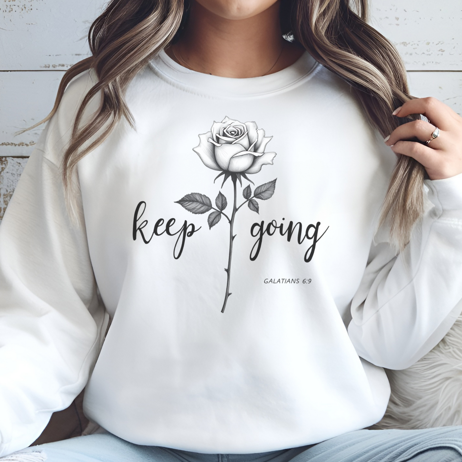 Keep Going long stem rose silhouette digital design on a woman’s white sweatshirt