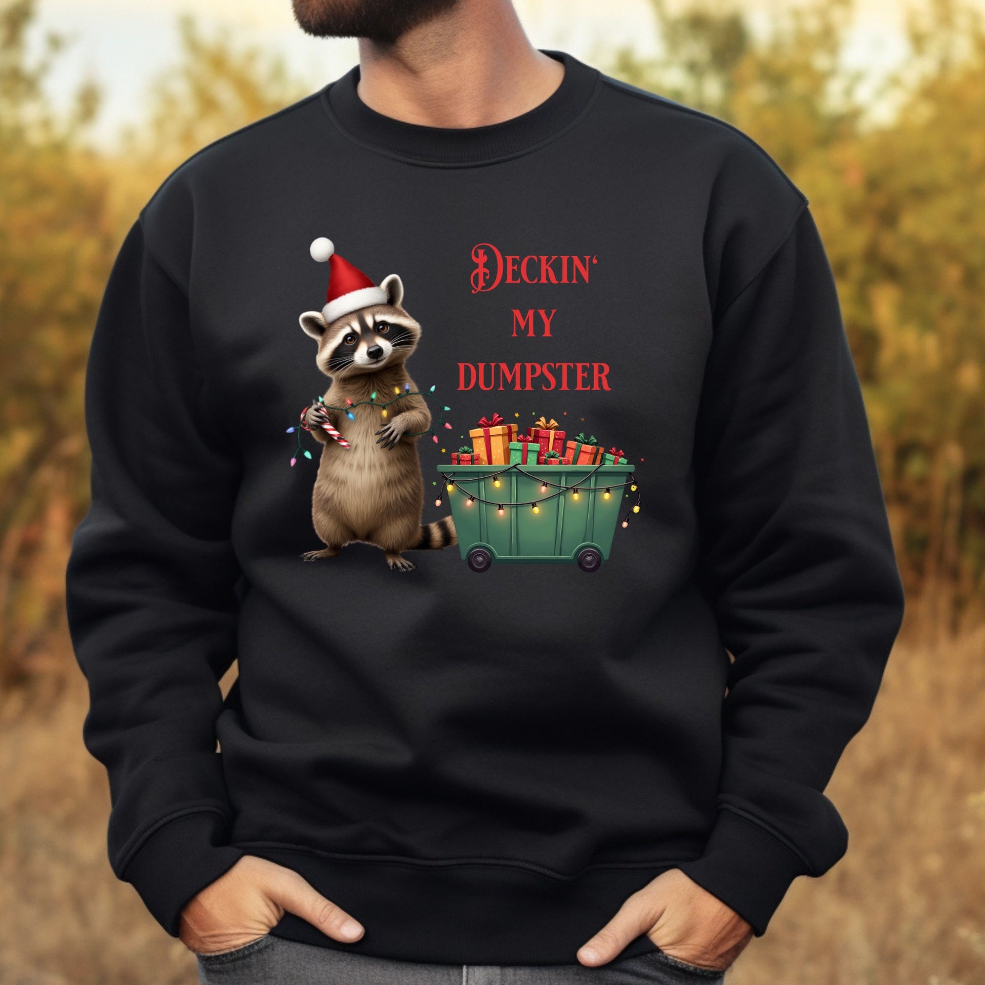 Black sweatshirt with a Christmas-themed design of a raccoon and text, worn by a person.
