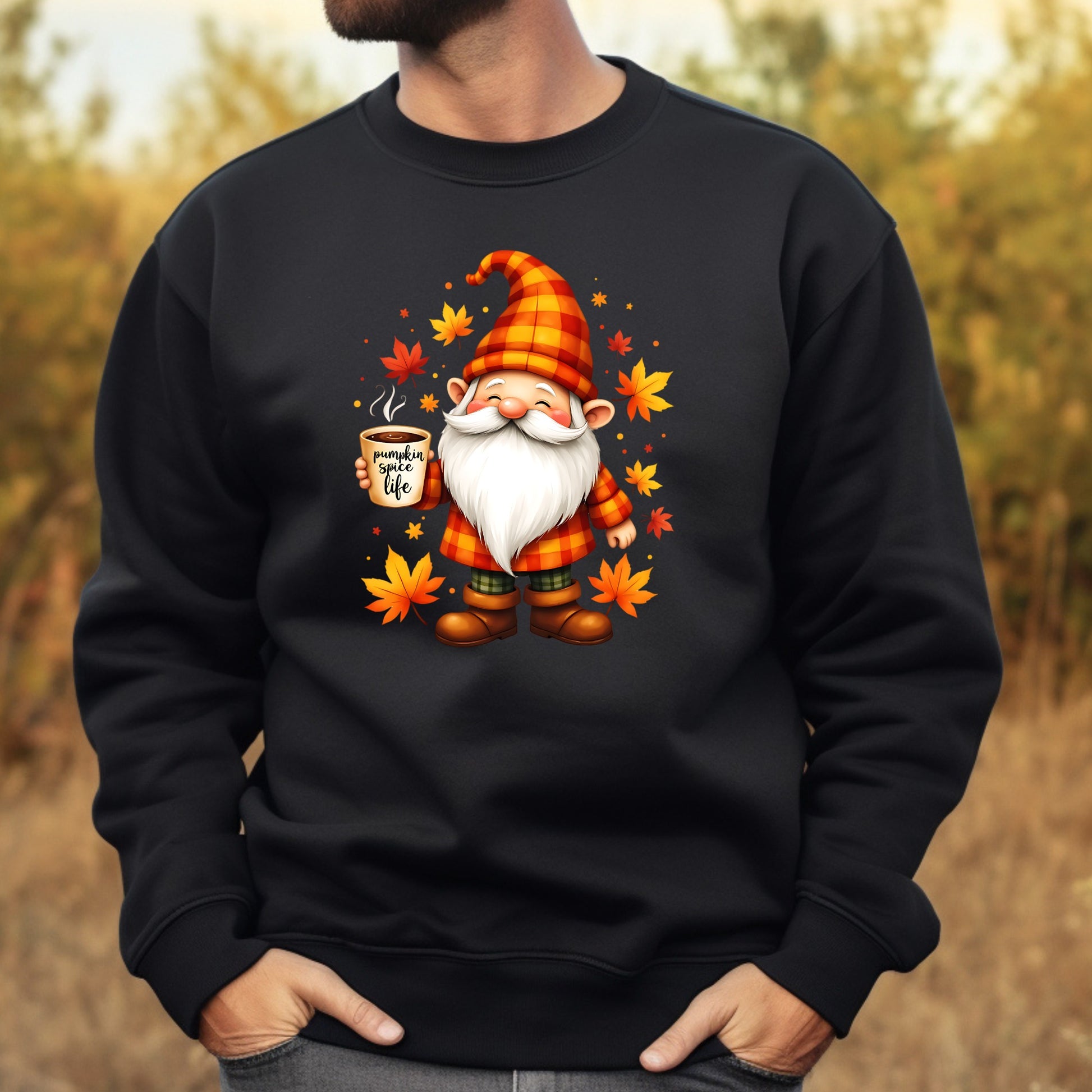 Black sweatshirt with a gnome graphic holding a coffee cup and autumn leaves on a blurred natural background.
