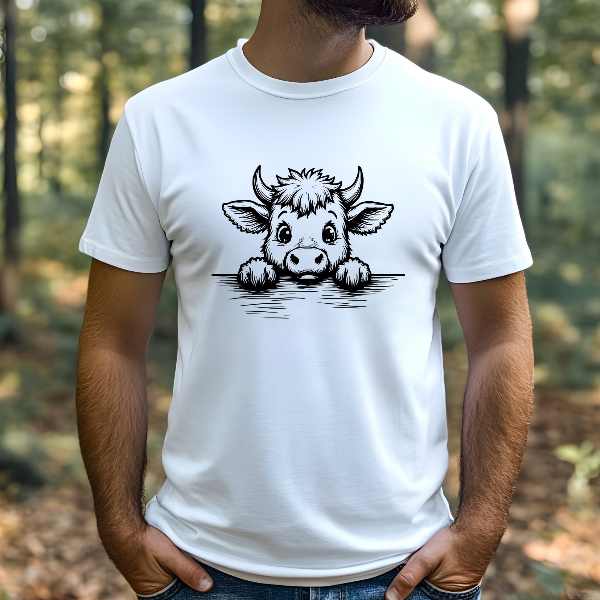 Man wearing a white t-shirt with a cartoon highland cow design outdoors.