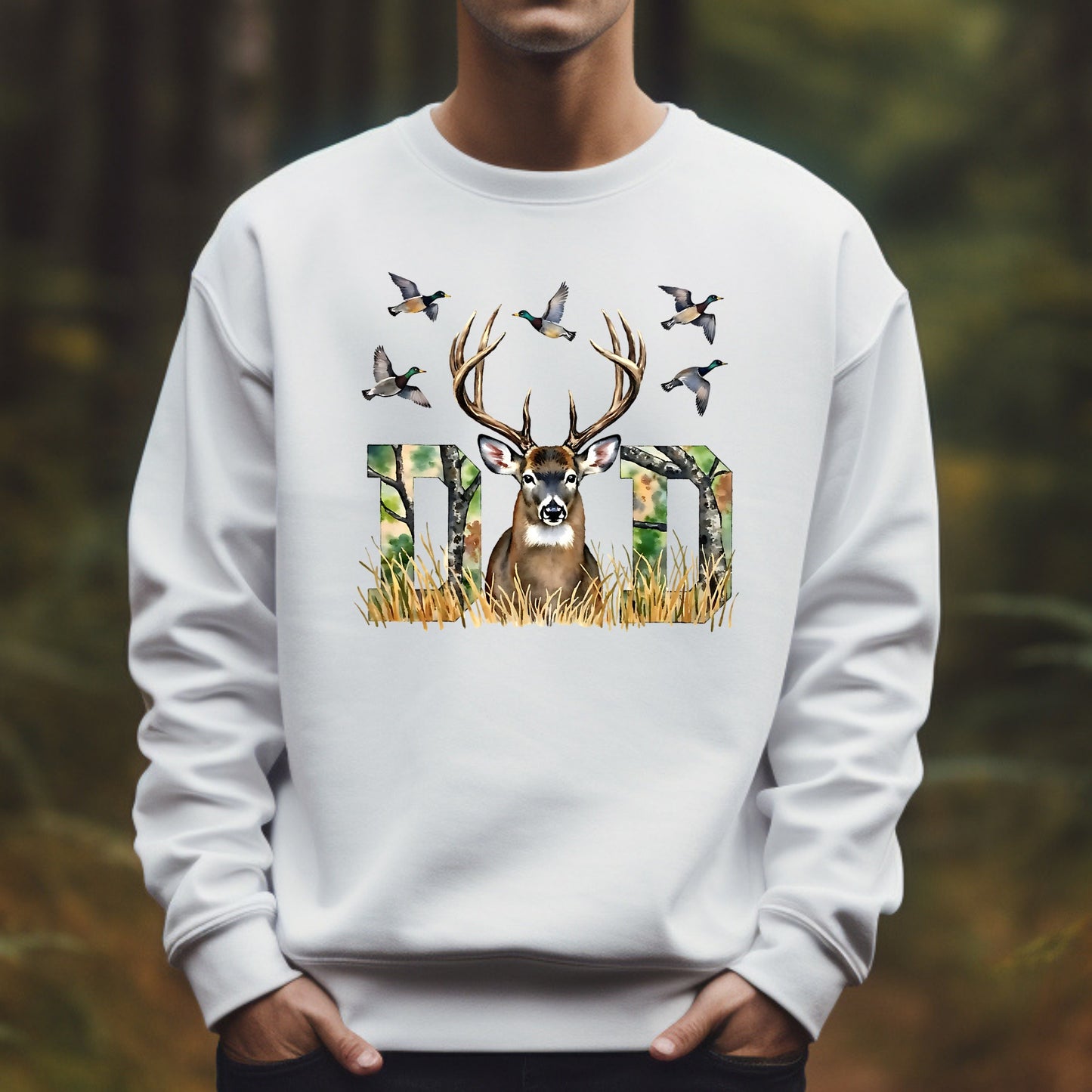 White sweatshirt with a deer and bird design worn by a man in a forest setting