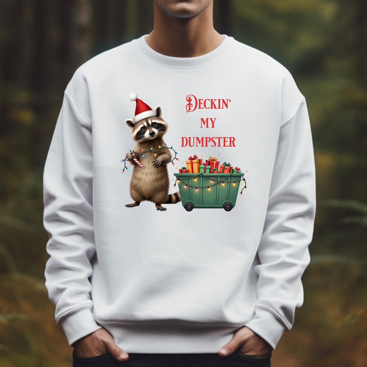 White sweatshirt with a Christmas-themed design of a raccoon and text, worn by a person outdoors.