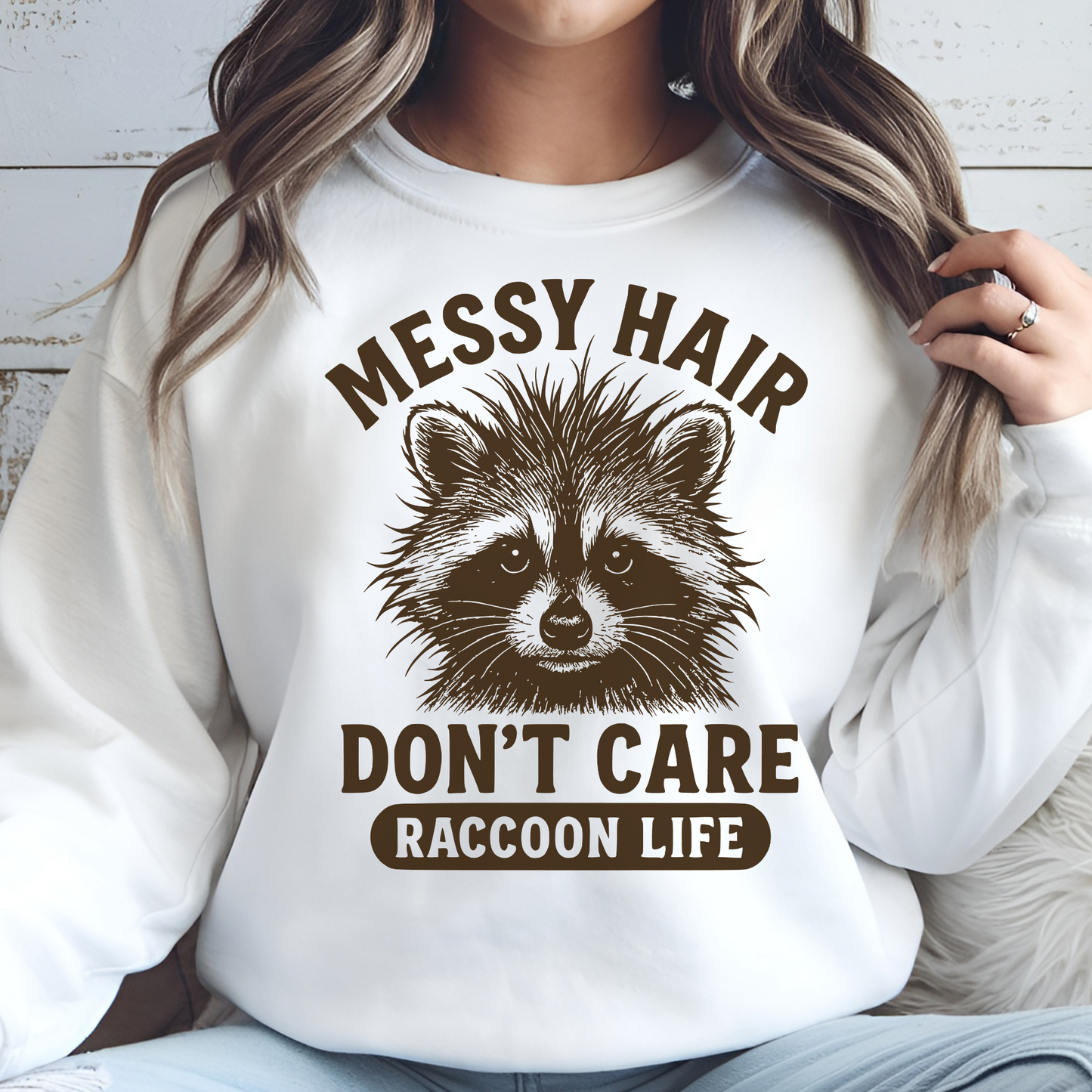 Messy Hair Don't Care Raccoon Life digital design on a woman's white sweatshirt