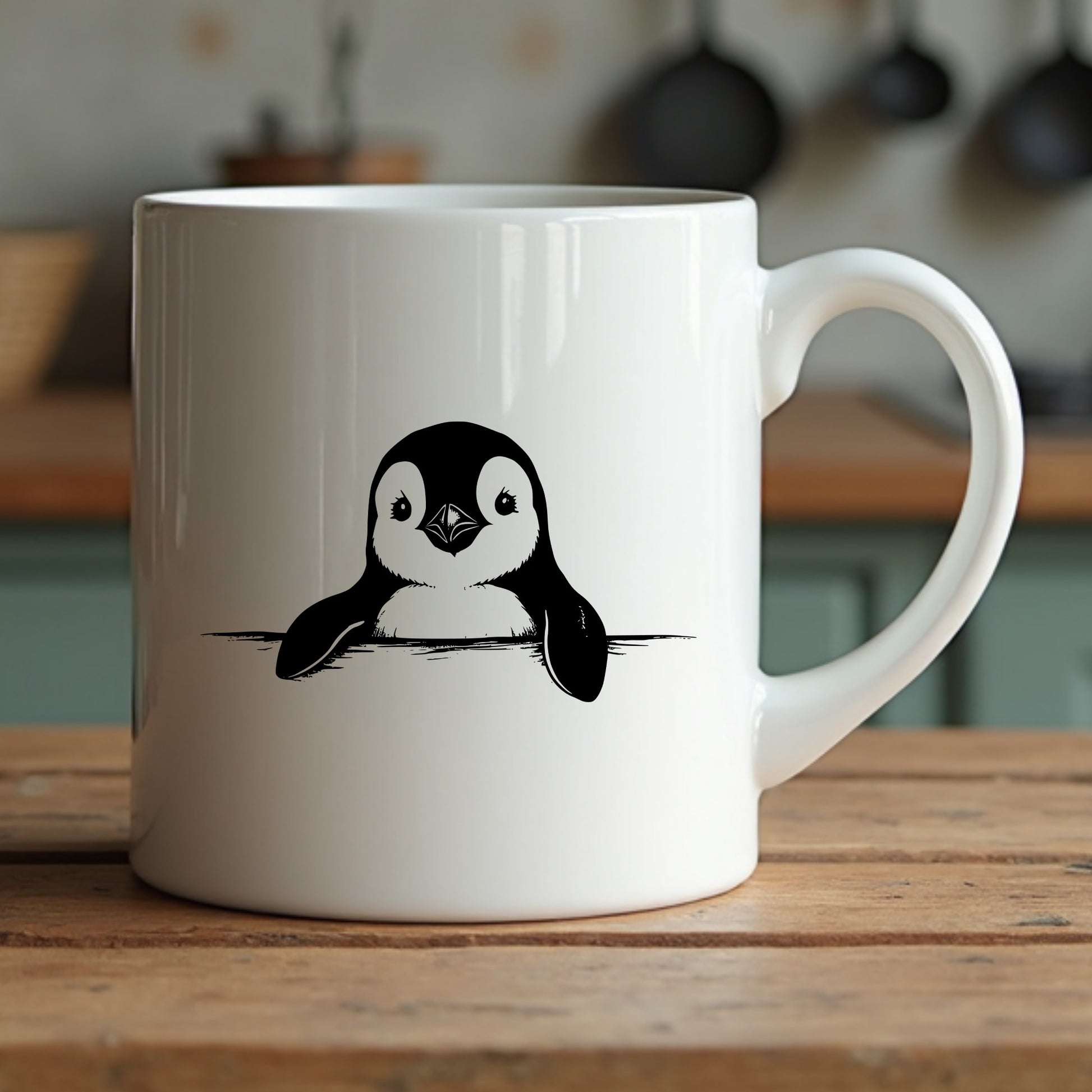 White mug with a penguin design on a wooden surface in a kitchen setting