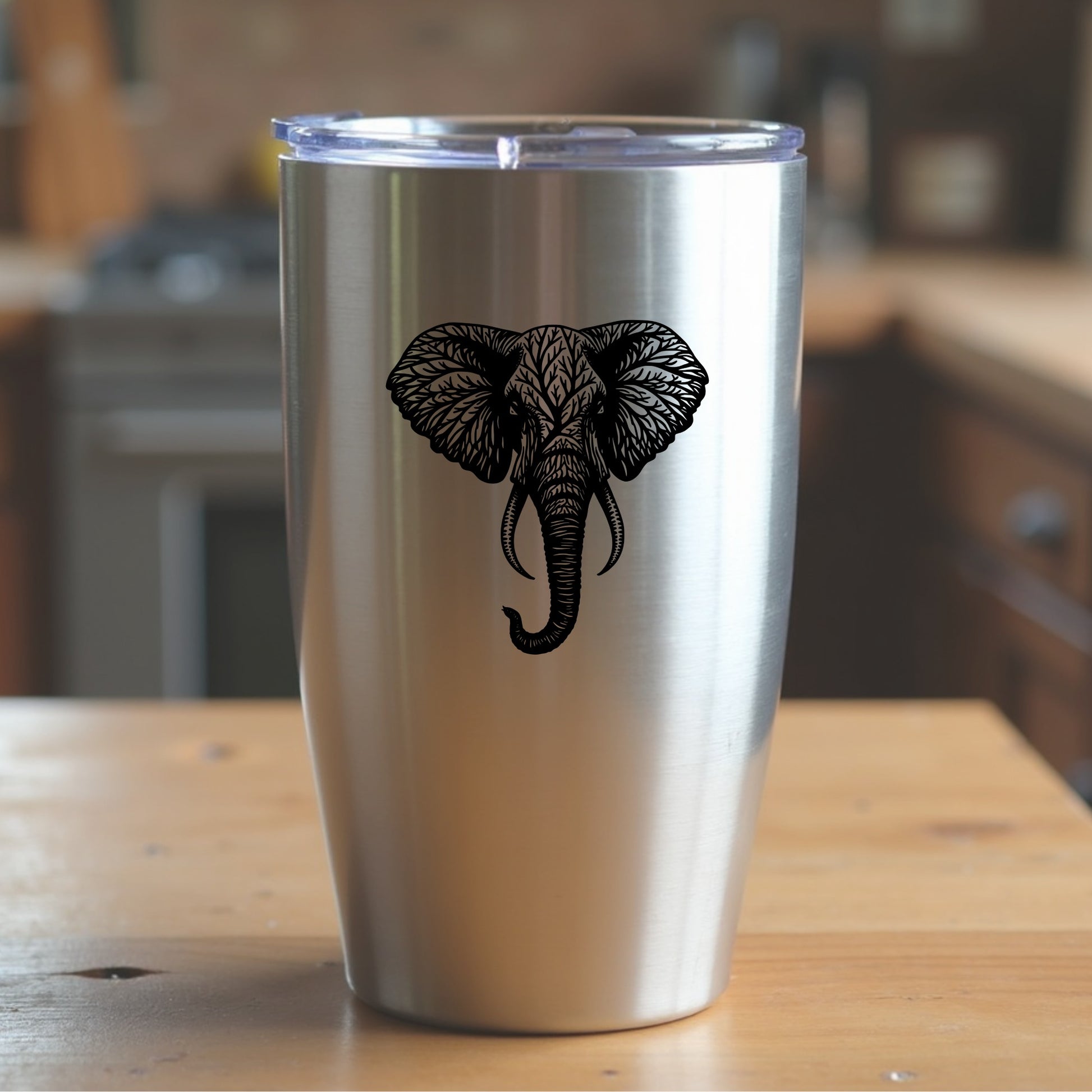 Stainless steel tumbler with an elephant design sitting on a wooden surface in a kitchen setting