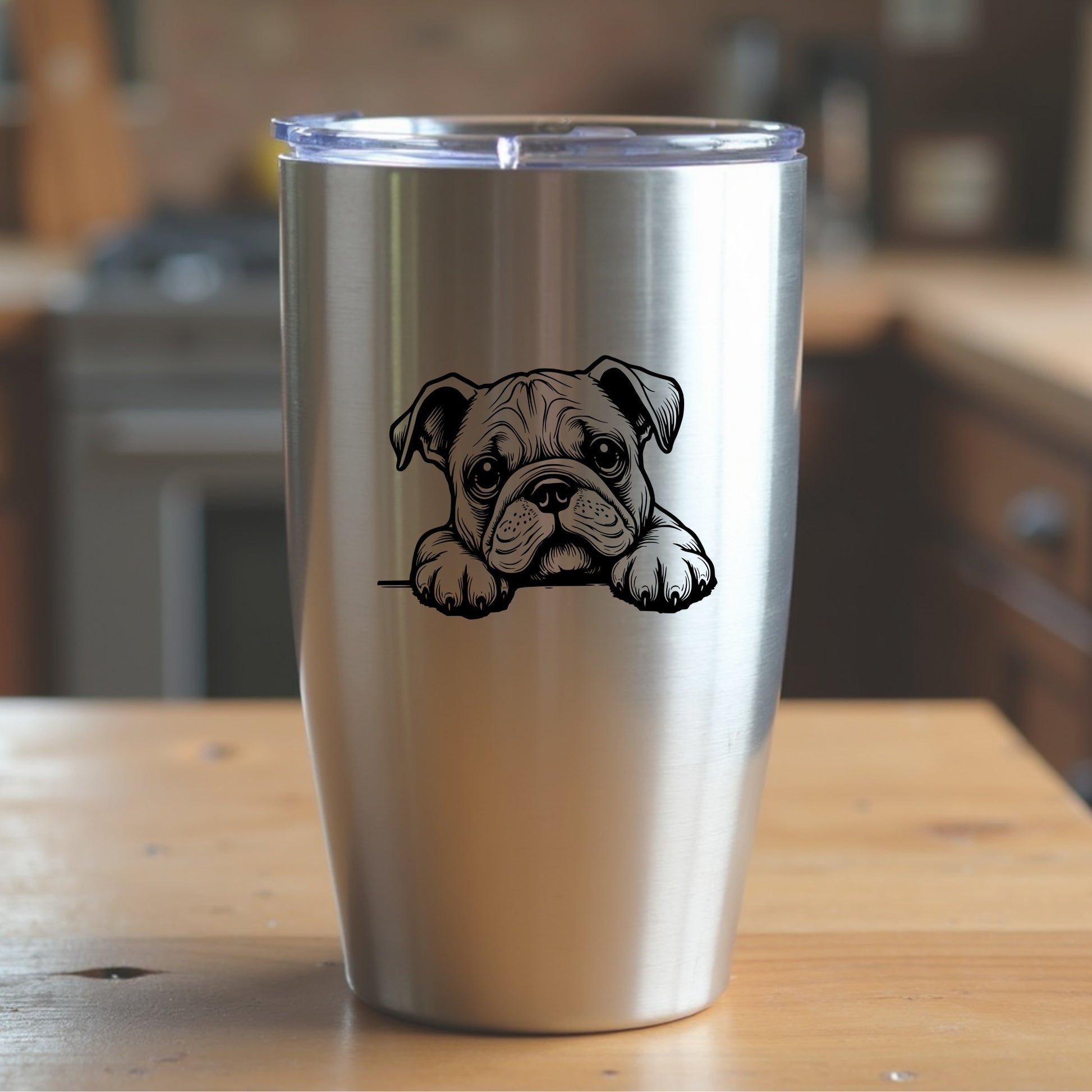 Silver tumbler with a bulldog design sitting on a wooden surface in a kitchen setting