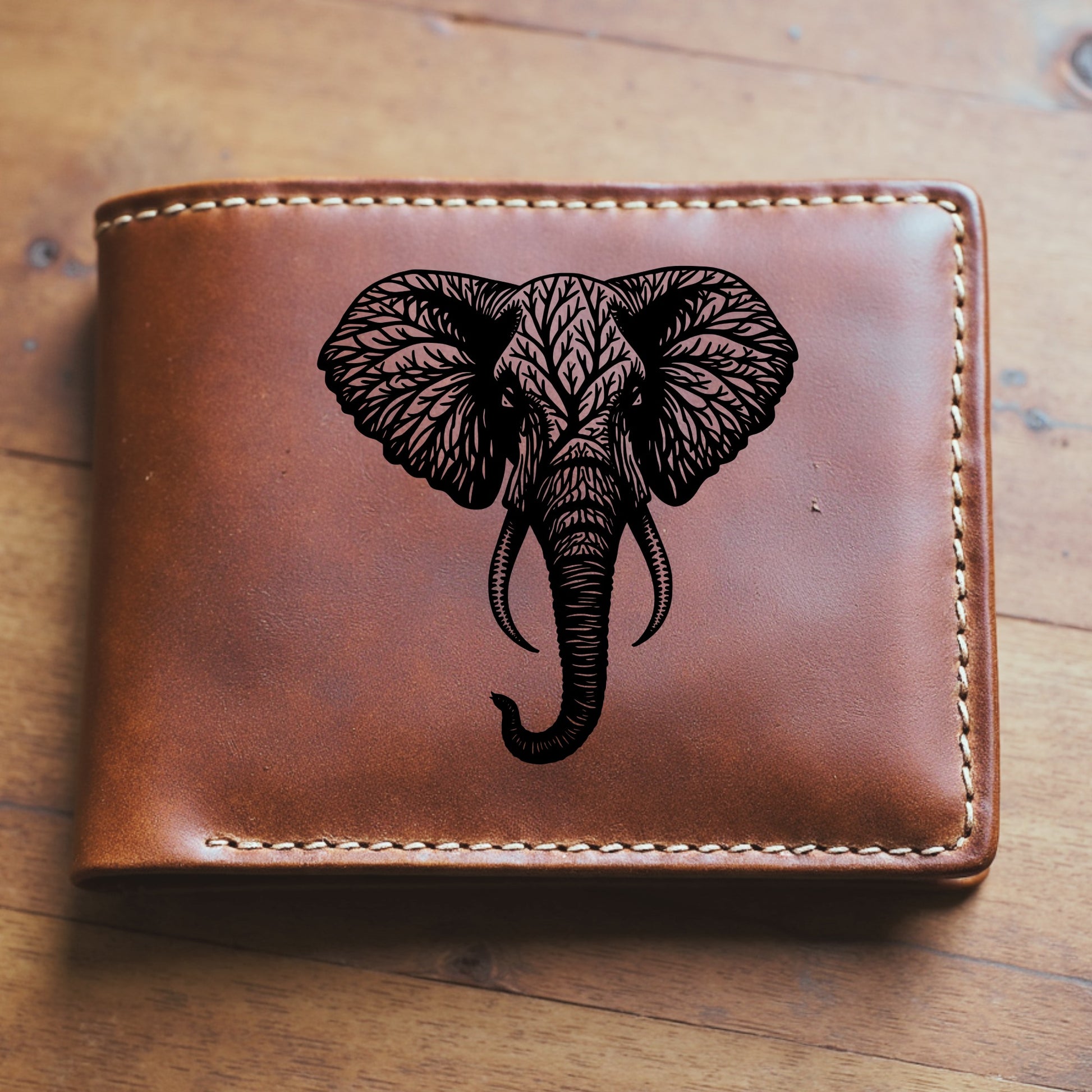 Brown leather wallet with an elephant engraving sitting on a wooden surface