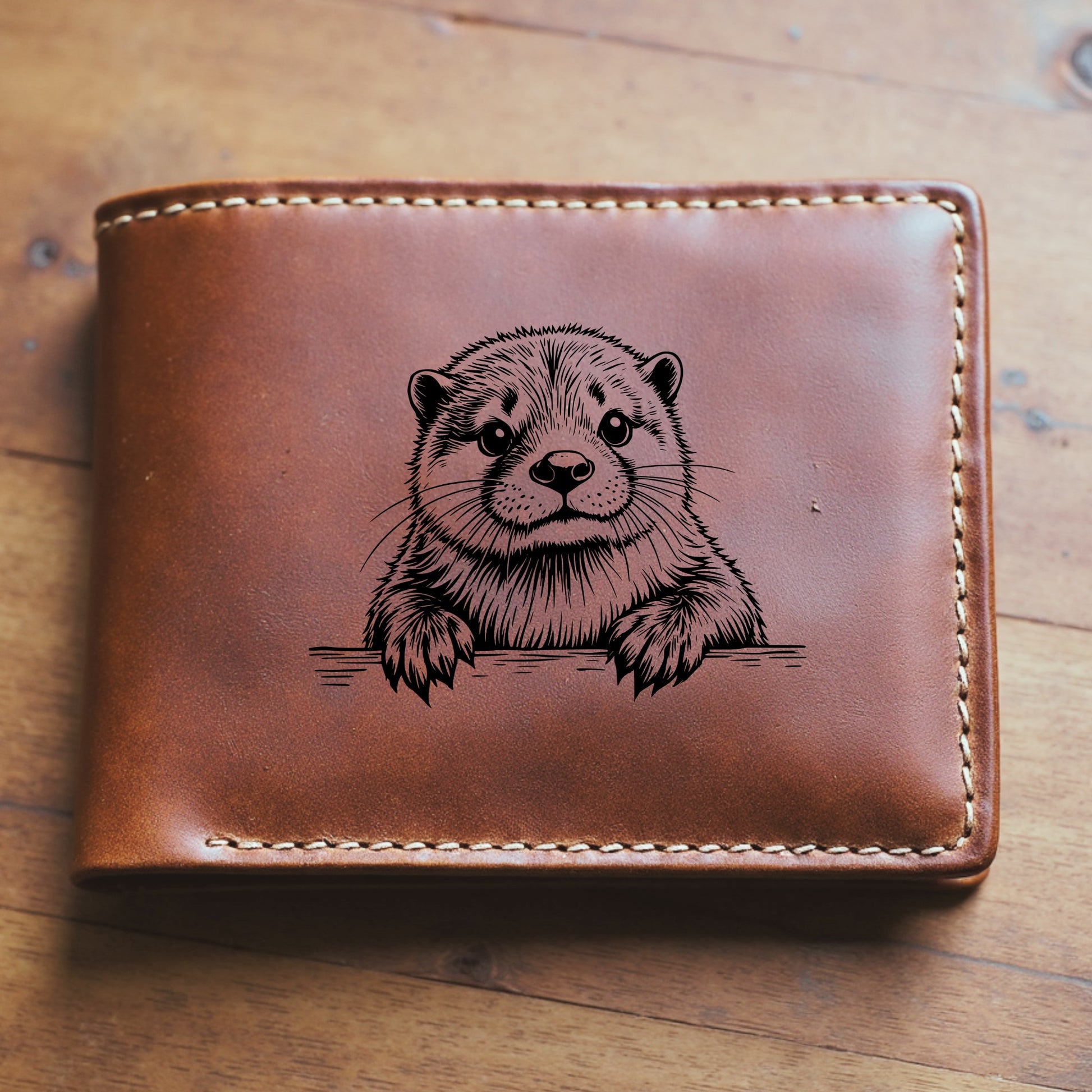 Brown leather wallet with an engraved otter design on a wooden surface