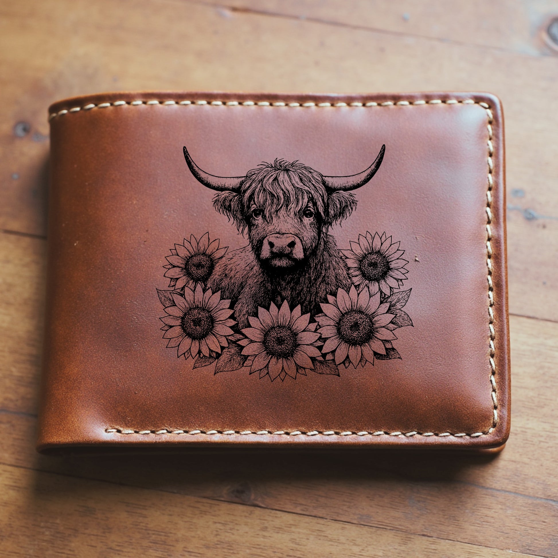 Brown leather wallet with a highland cow and sunflower design on a wooden surface