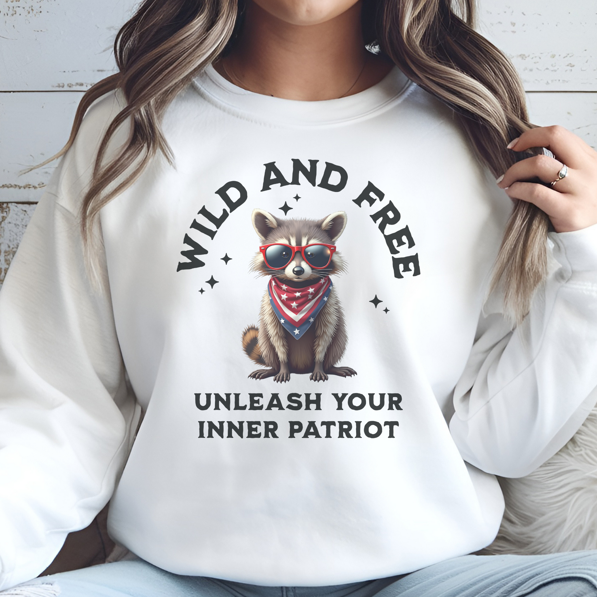 Wild And Free Patriotic Raccoon PNG digital design on a woman's white sweatshirt
