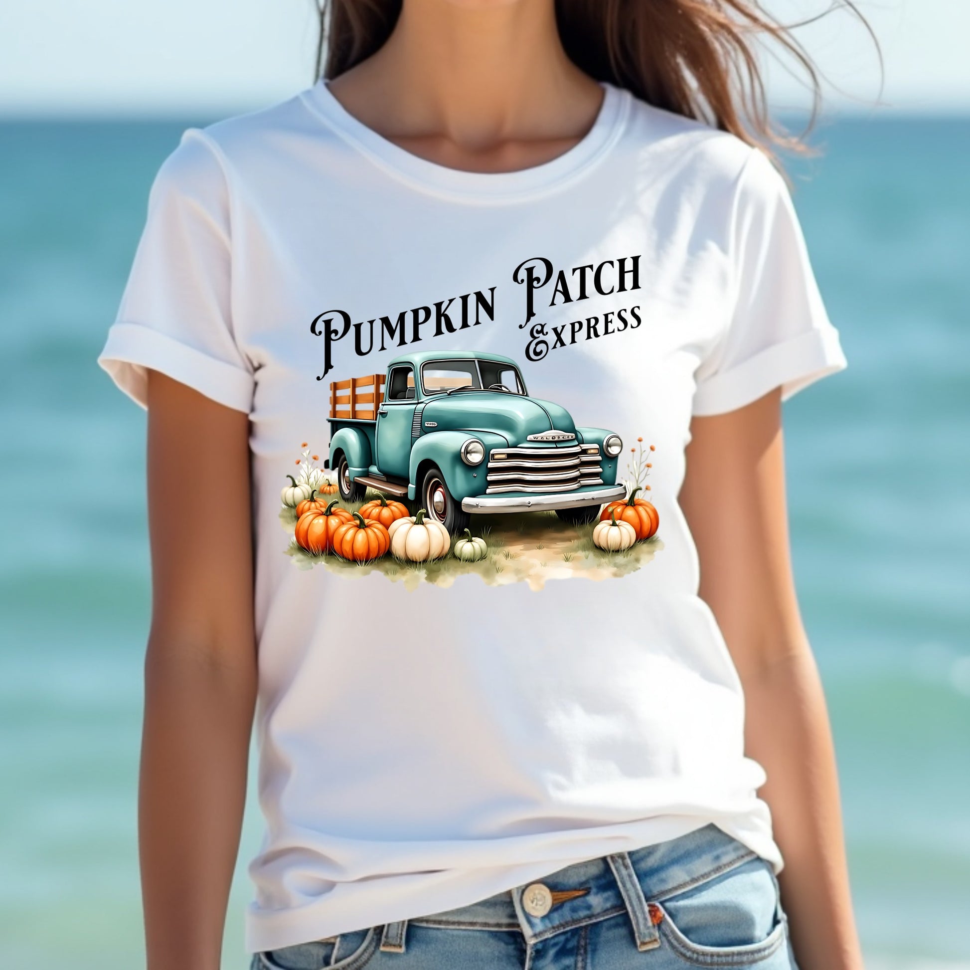Woman wearing a white t-shirt with a pumpkin patch truck graphic in front of a blurred beach background