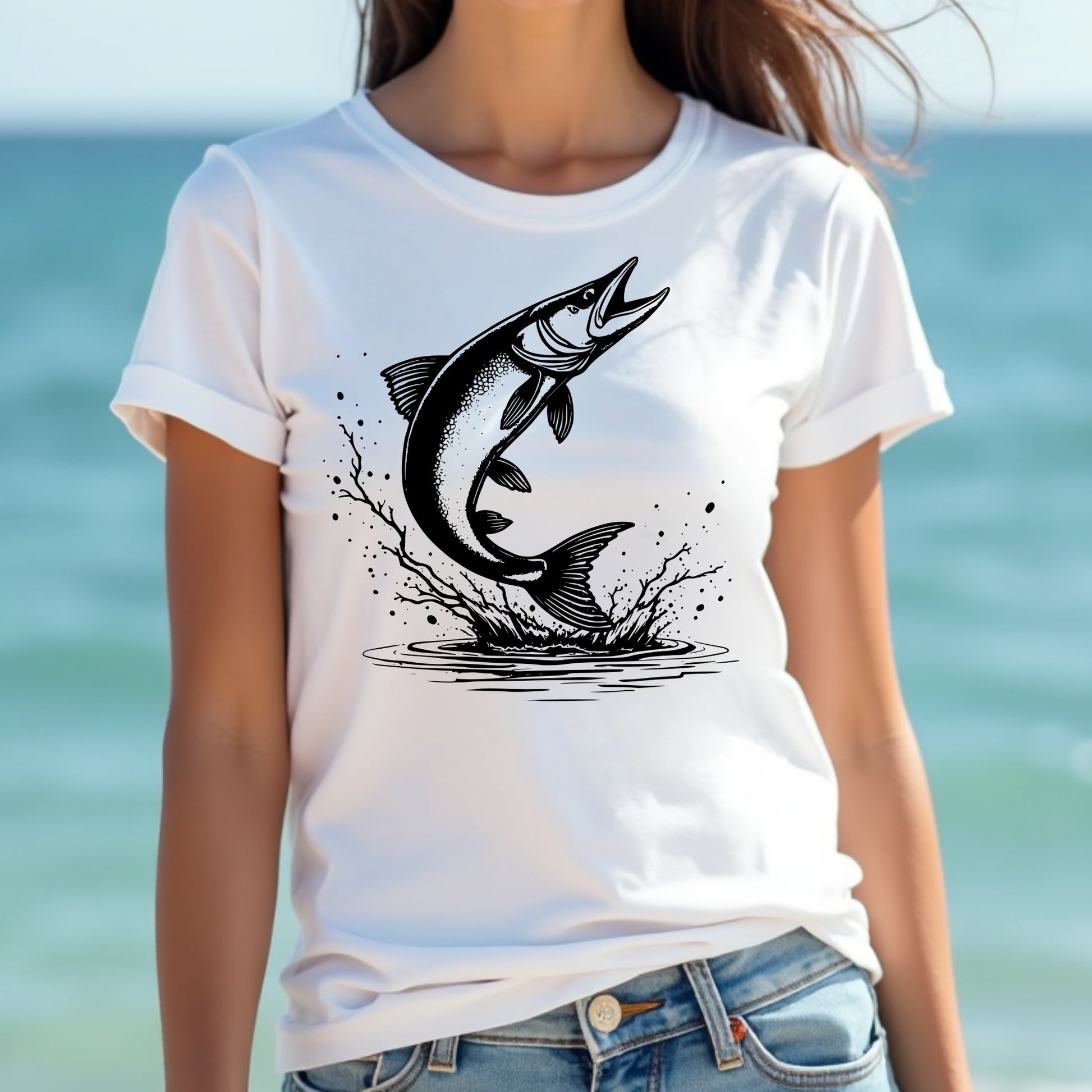 Woman wearing a white t-shirt with a black muskie fish graphic against a blurred beach background