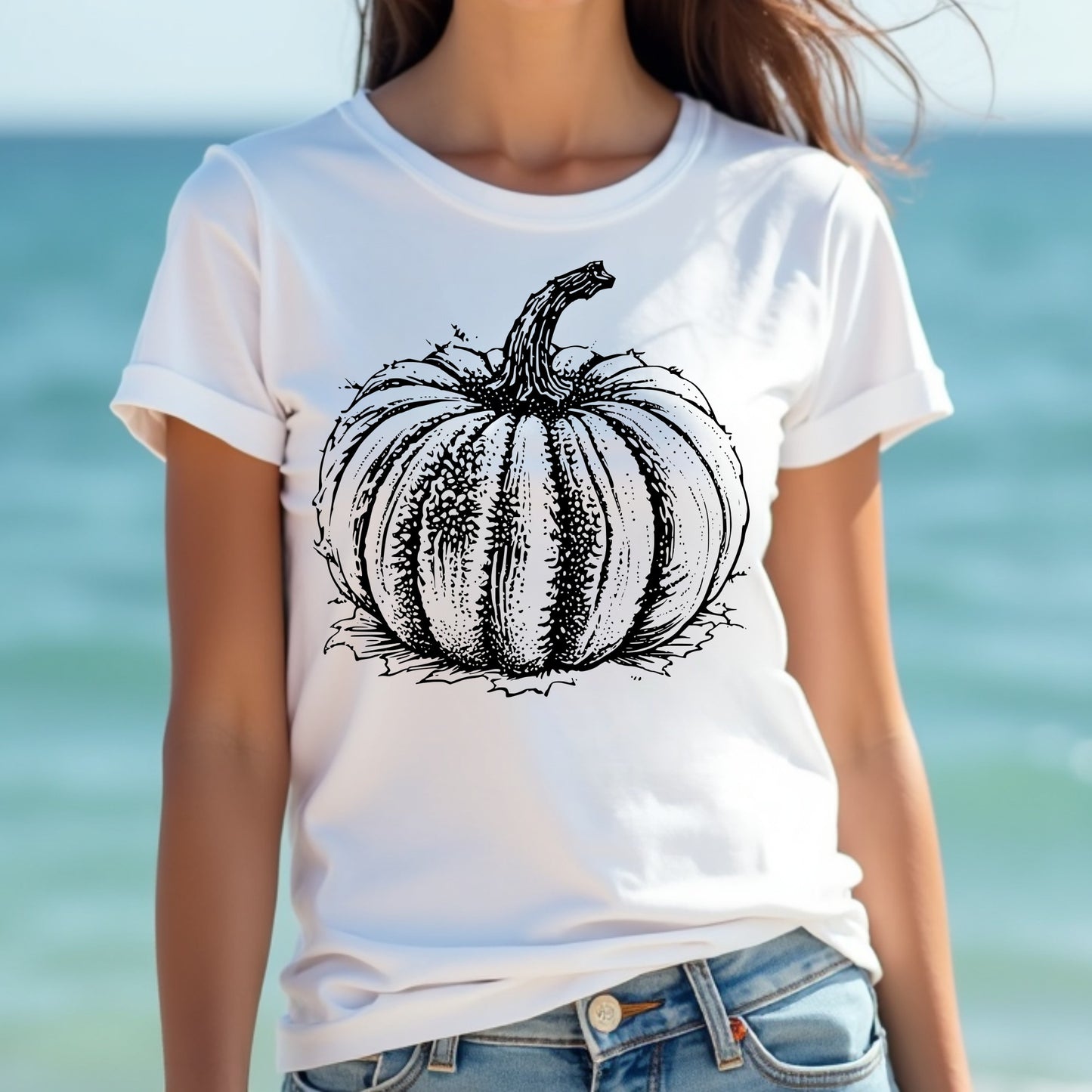 Woman wearing a white t-shirt with a black pumpkin graphic against a blurred beach background