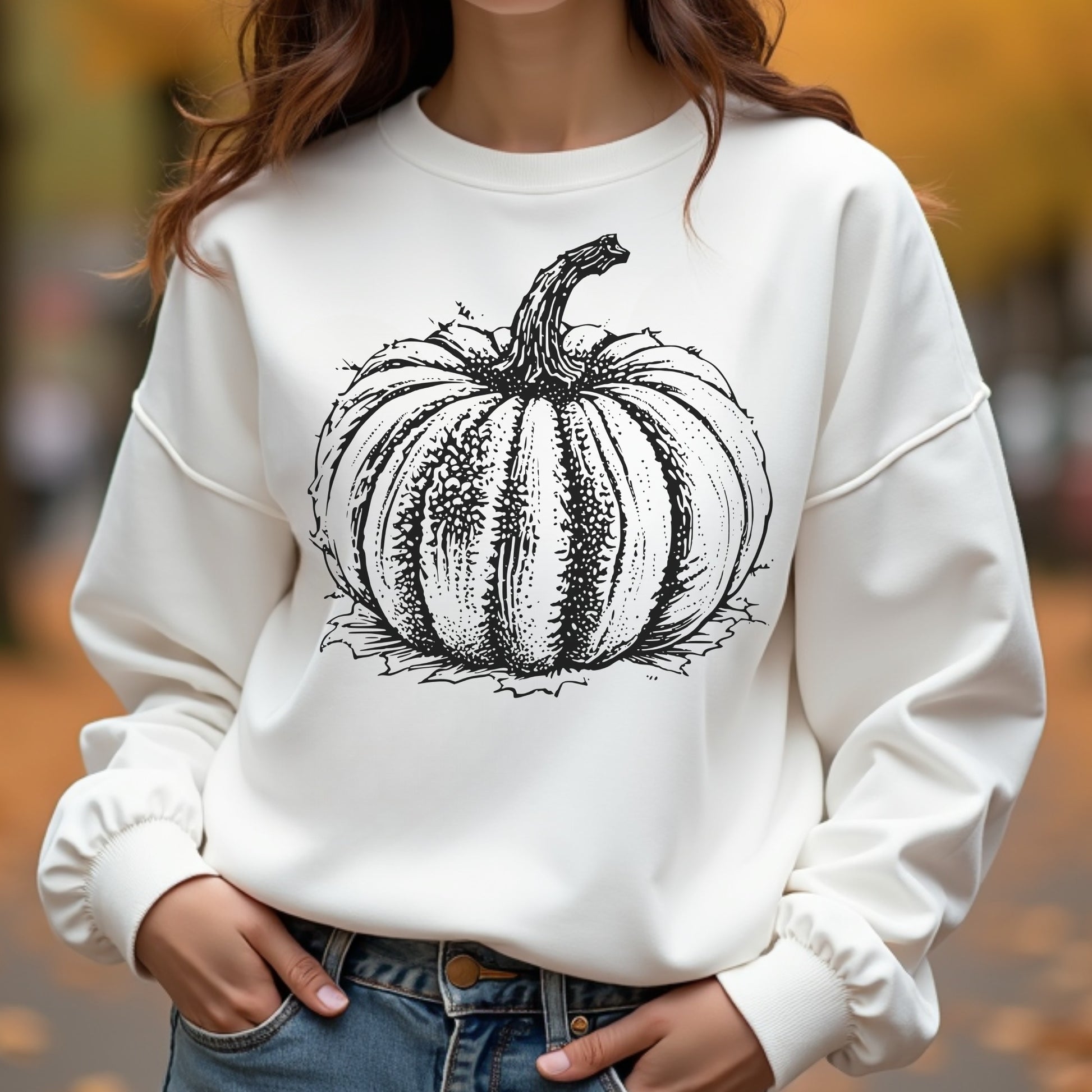 Woman wearing a white sweatshirt with a black pumpkin graphic in an outdoor setting.