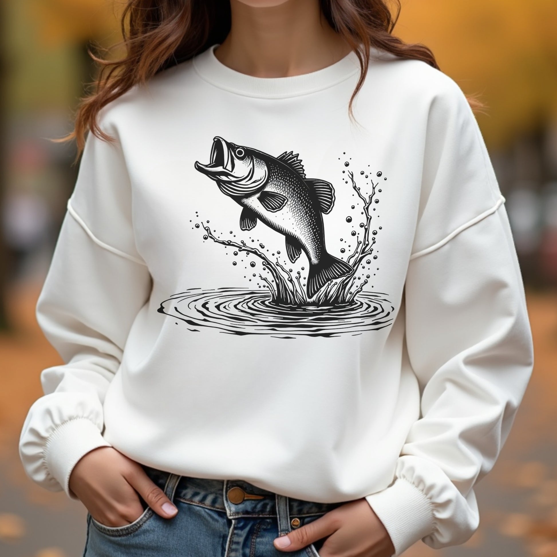 White sweatshirt with a bigmouth bass fish graphic worn by a woman outdoors.