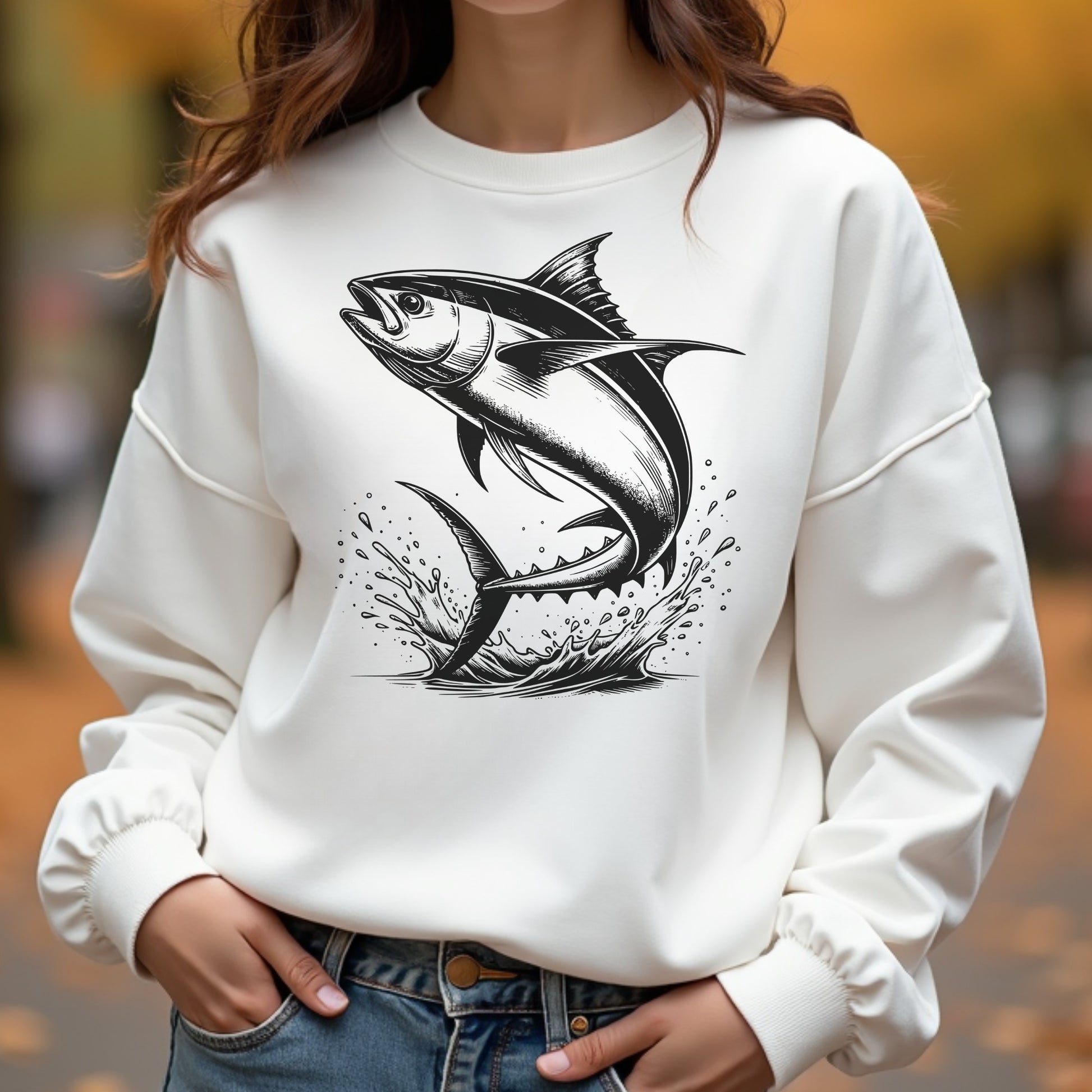Woman wearing a white sweatshirt with a black tuna fish design outdoors.