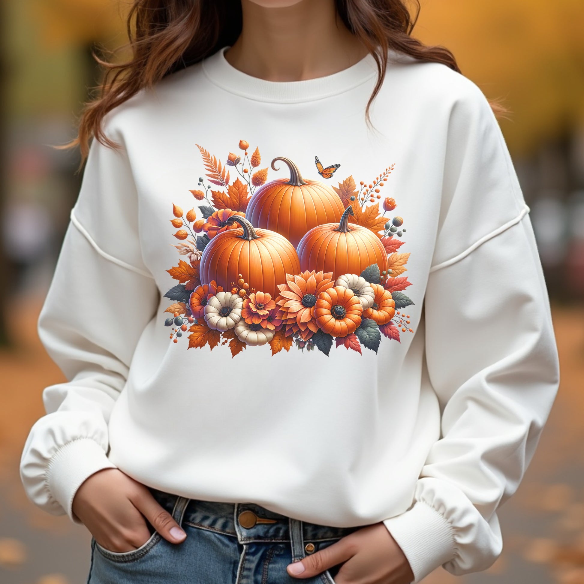 White sweatshirt with pumpkin and floral design worn by a woman outdoors.