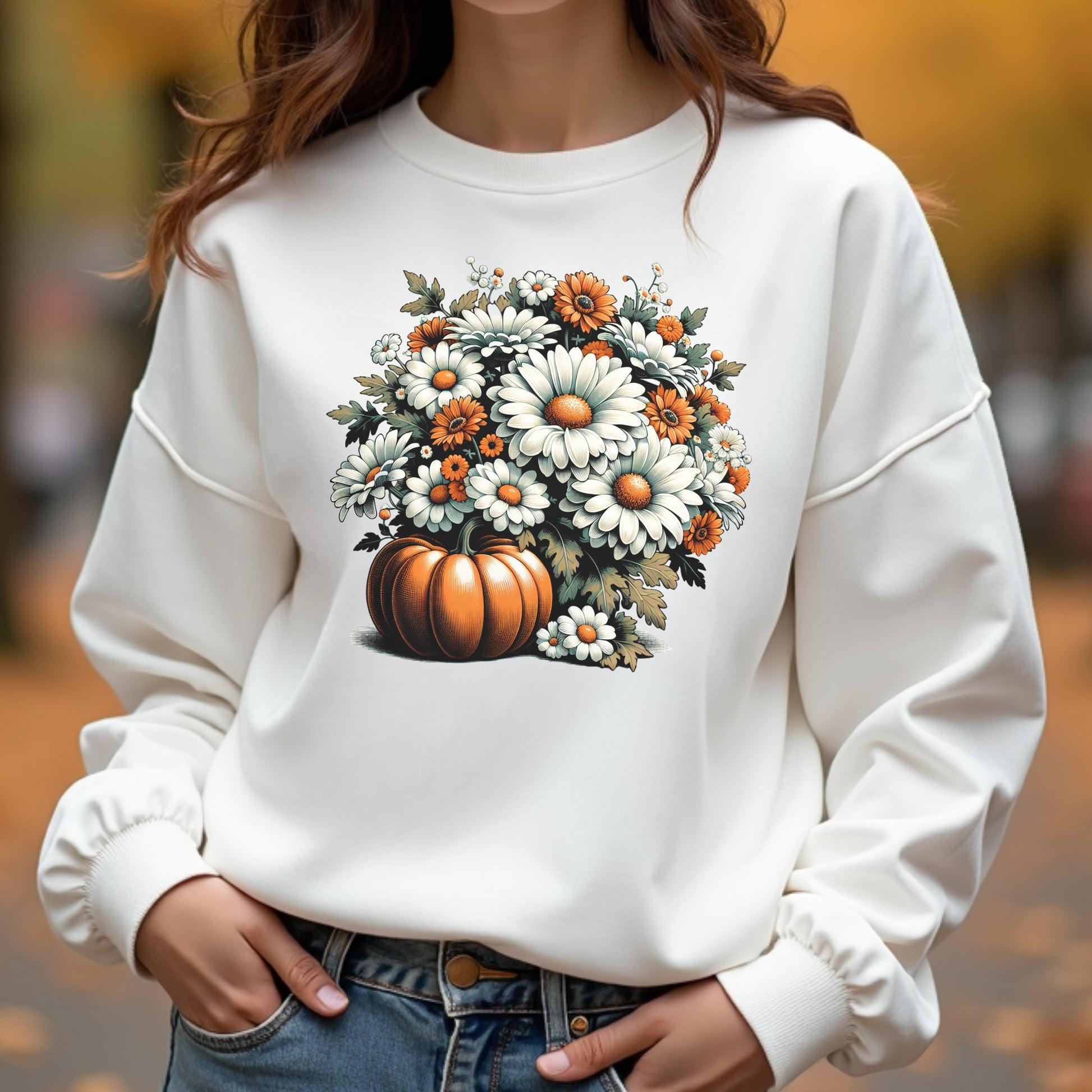 Person wearing a white sweatshirt with a pumpkin and floral design outdoors.