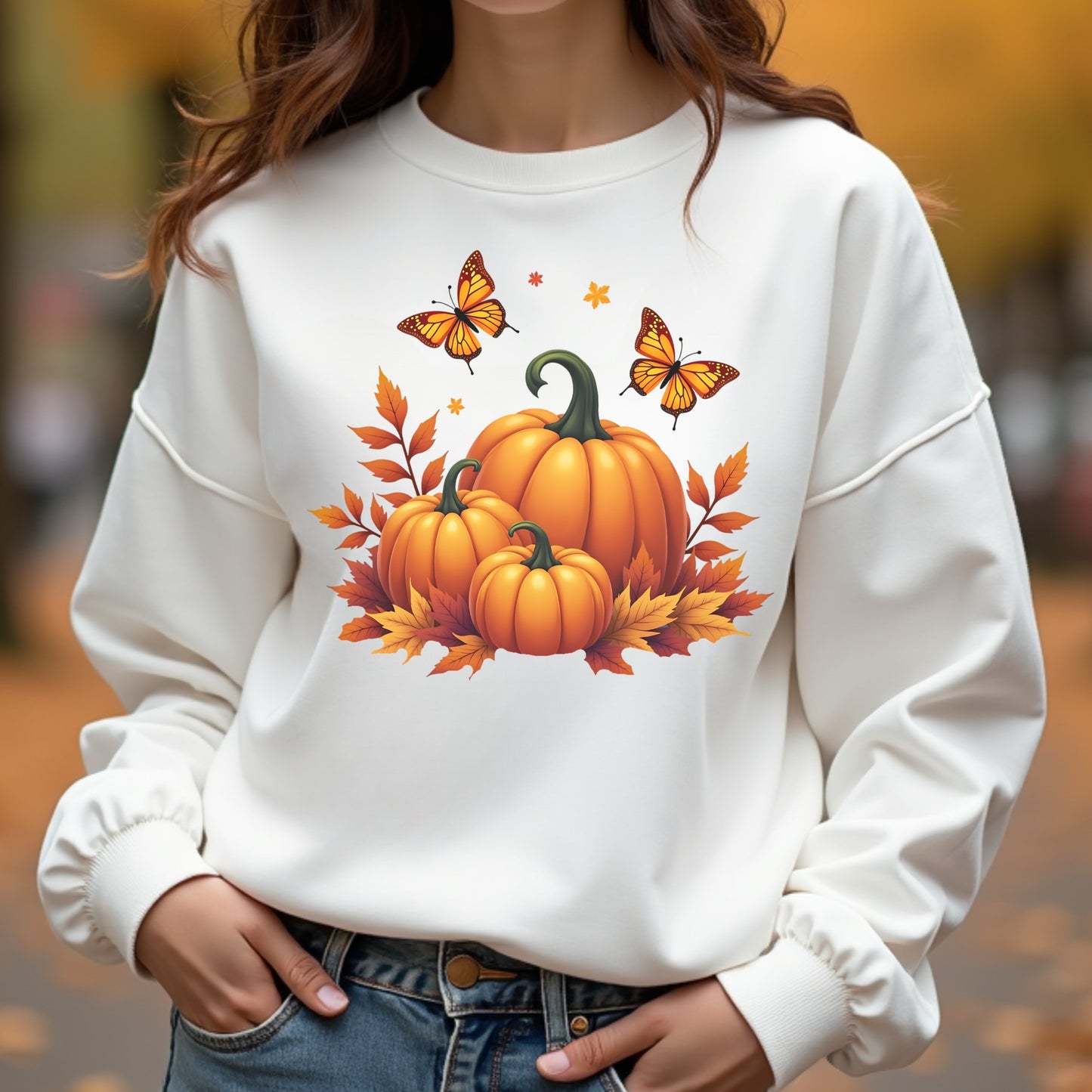 Woman wearing a white sweatshirt with pumpkins and butterflies design outdoors.