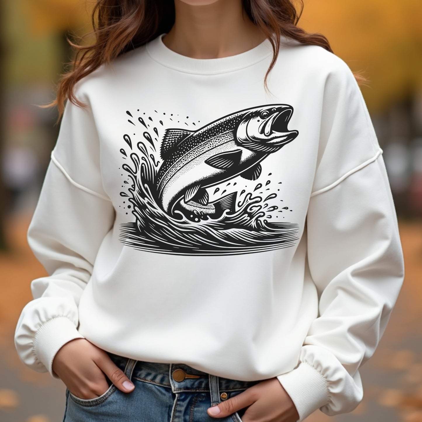 White sweatshirt with a fish graphic worn by a woman outdoors.