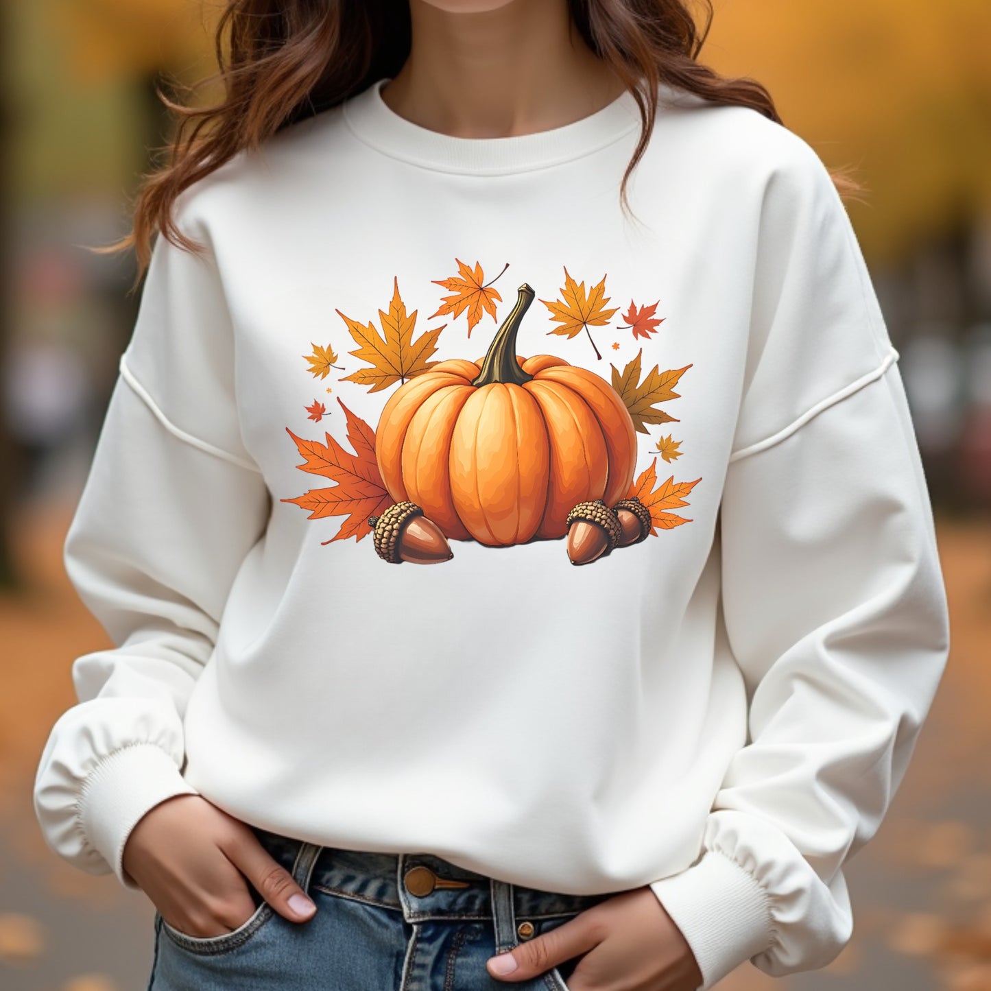 Woman wearing a white sweatshirt with a pumpkin and leaf design outdoors.