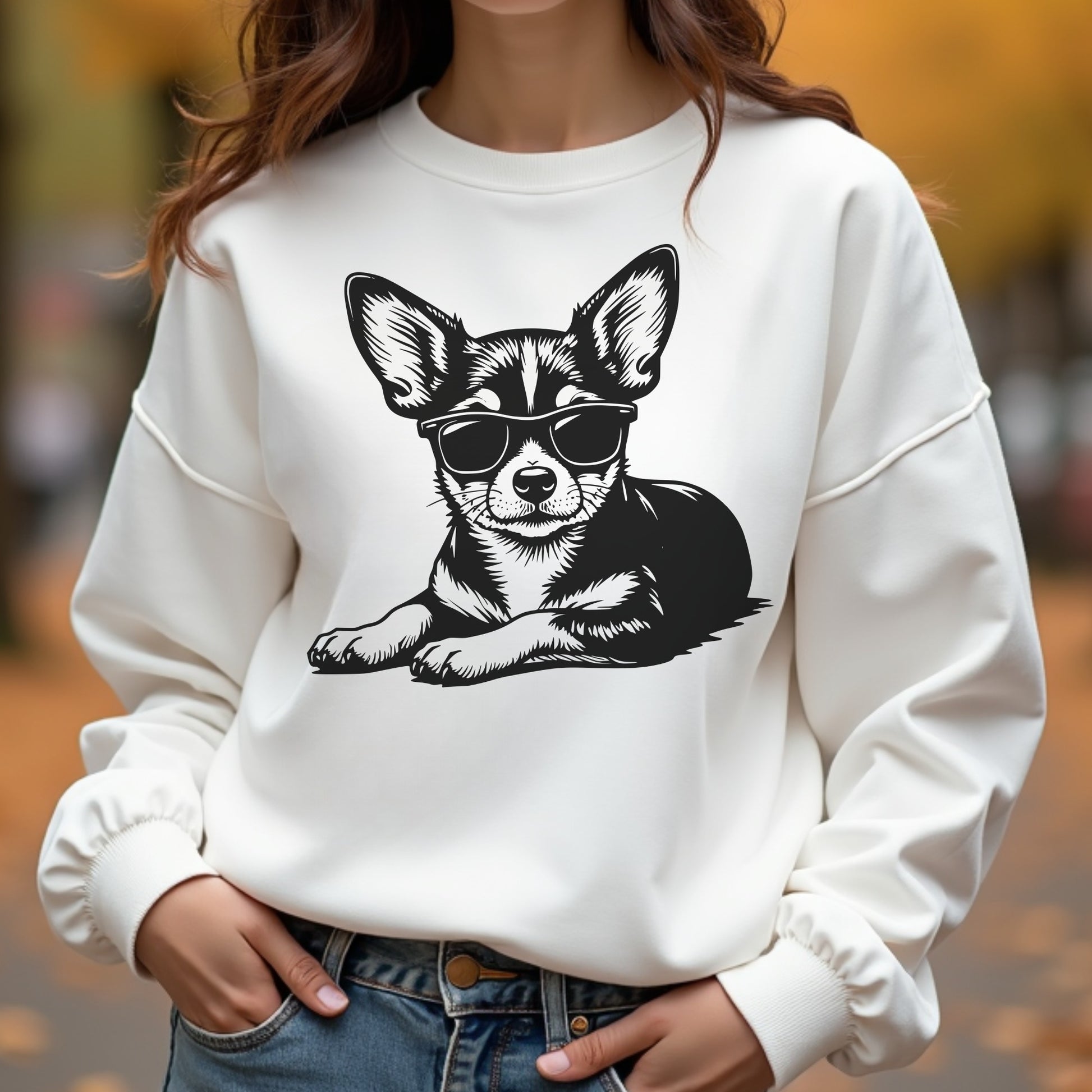 White sweatshirt with a chihuahua graphic wearing sunglasses on a blurred outdoor background