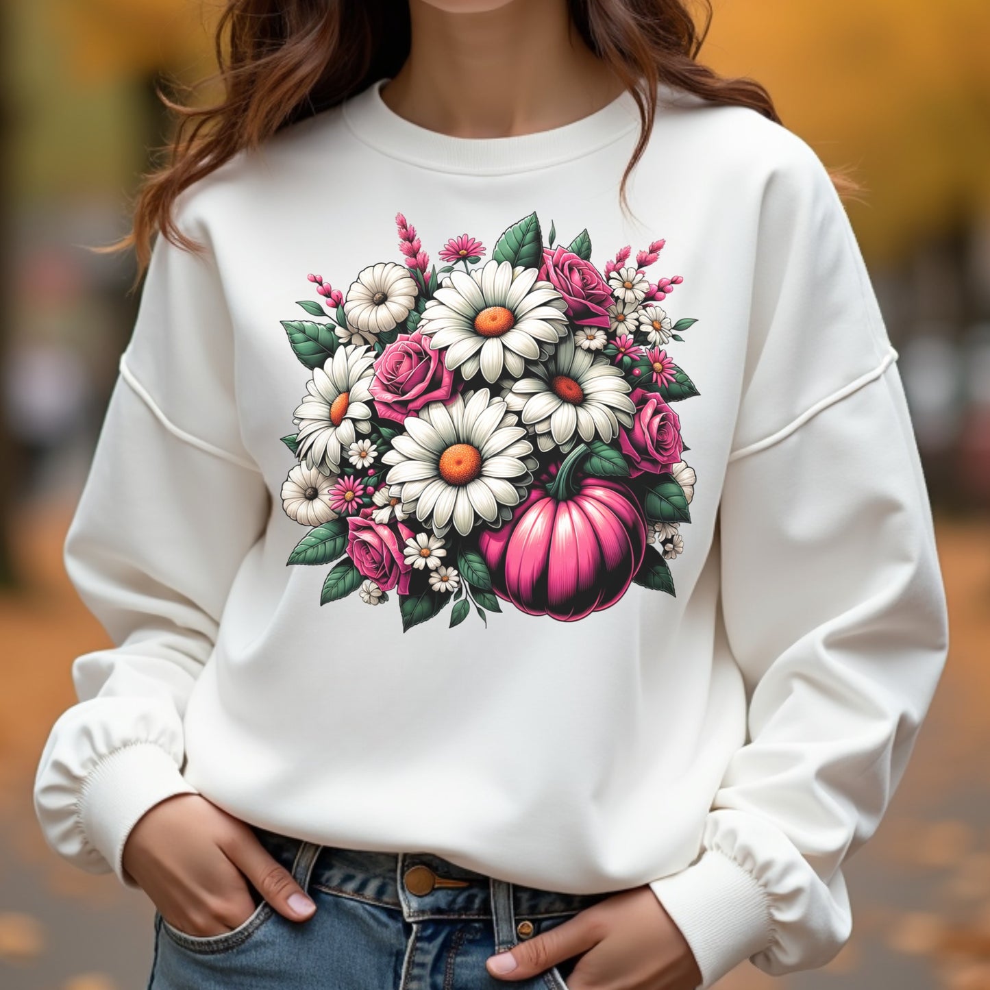 White sweatshirt with floral design featuring pumpkins and flowers, worn by a person outdoors.