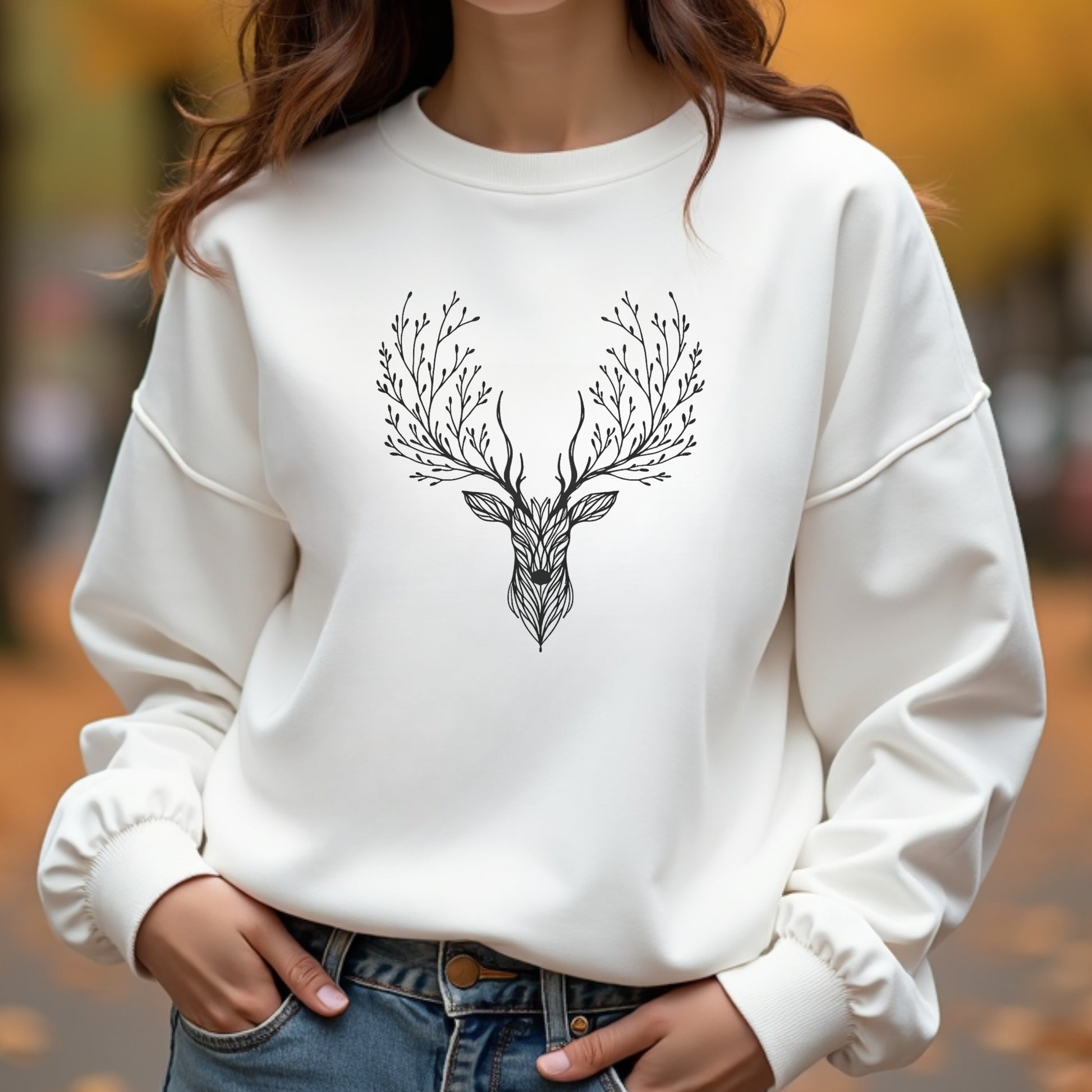 A woman wearing a white deer tree antlers sweatshirt on an autumn day.